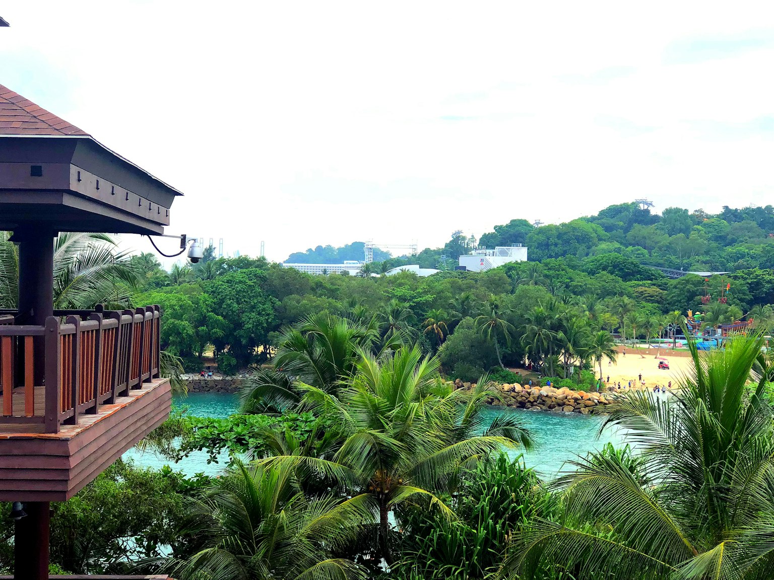 Pemandangan indah dari balkon resort dengan pepohonan hijau dan pantai biru