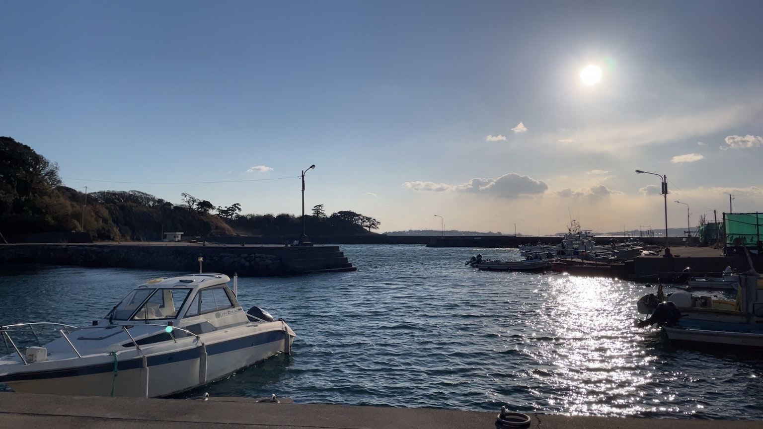 Boats moored near the shore under a bright sky