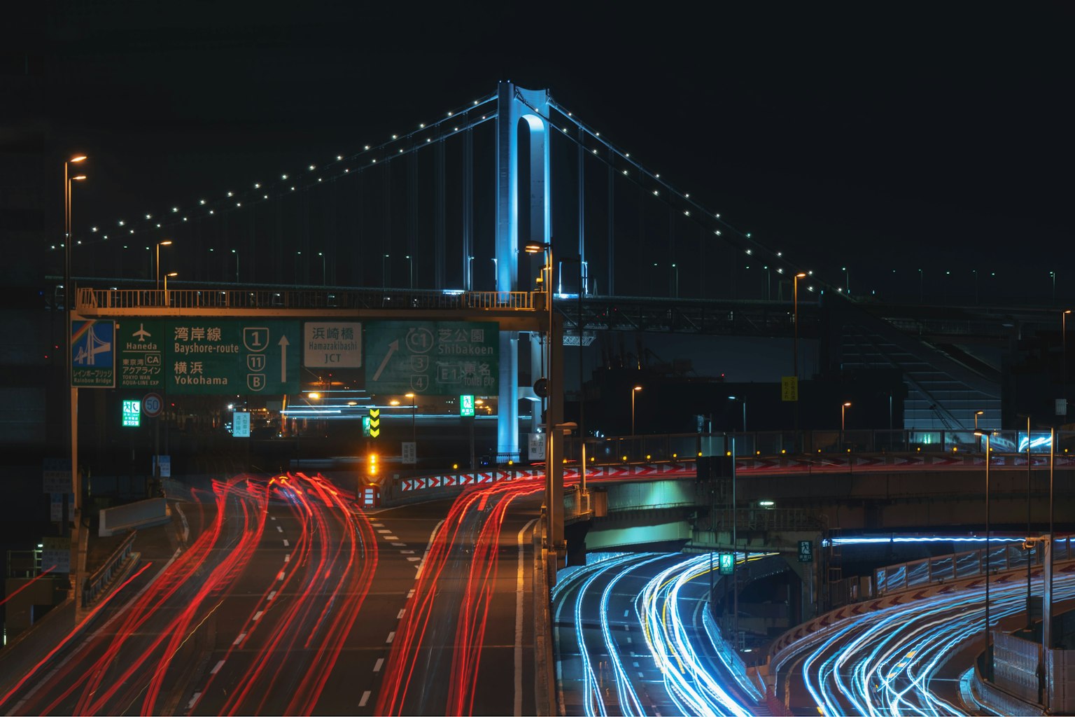 Vista nocturna de un puente con luces de coches en movimiento iluminado Puente Arcoíris