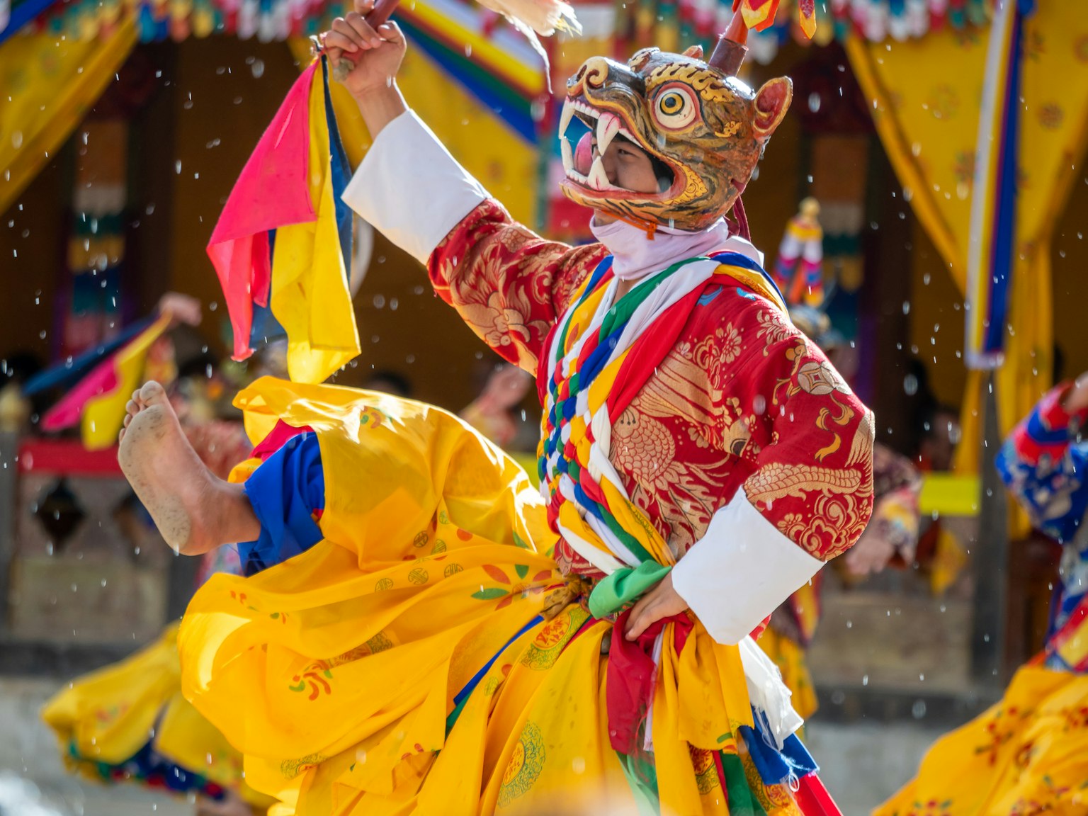Danzatore con costume colorato e maschera che si esibisce in una scena di festival tradizionale