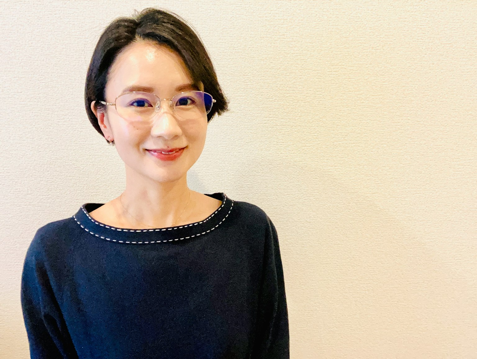 一位穿着蓝色毛衣的女性在明亮的背景前微笑