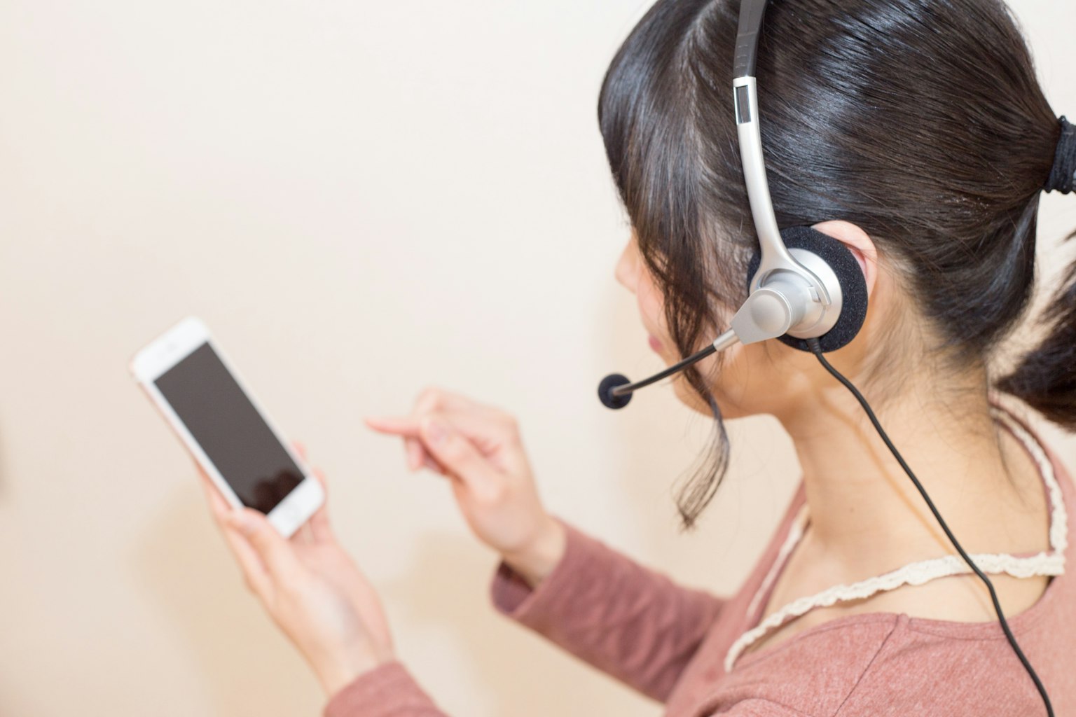 Woman using smartphone while wearing a headset