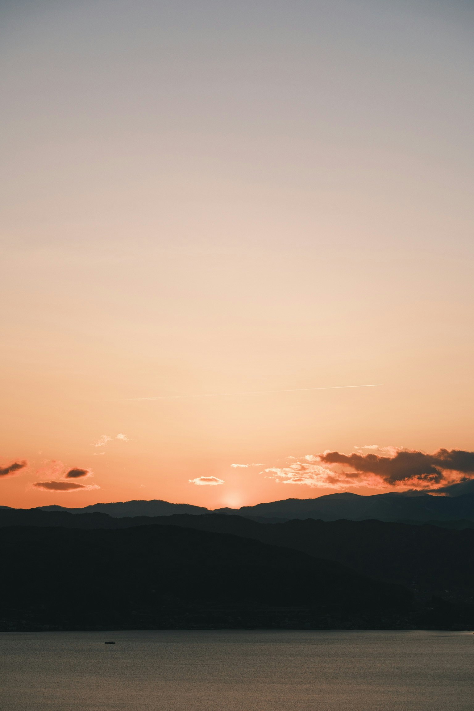 Ein schöner Sonnenuntergang hinter Bergen mit einem ruhigen See