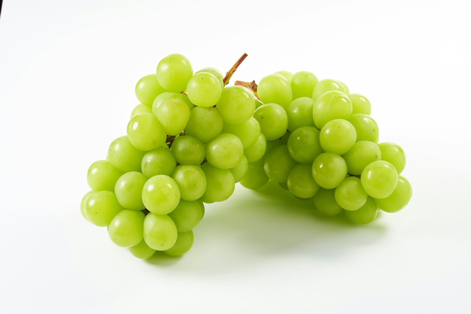 Fresh green grape clusters on a white background