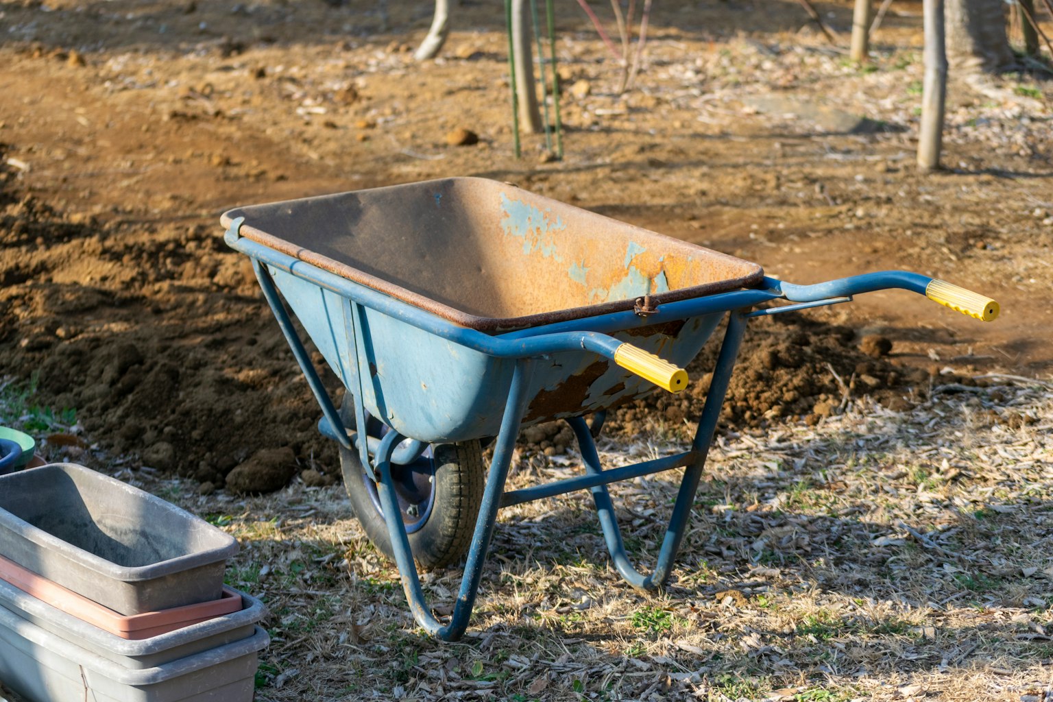 A blue wheelbarrow placed on the ground