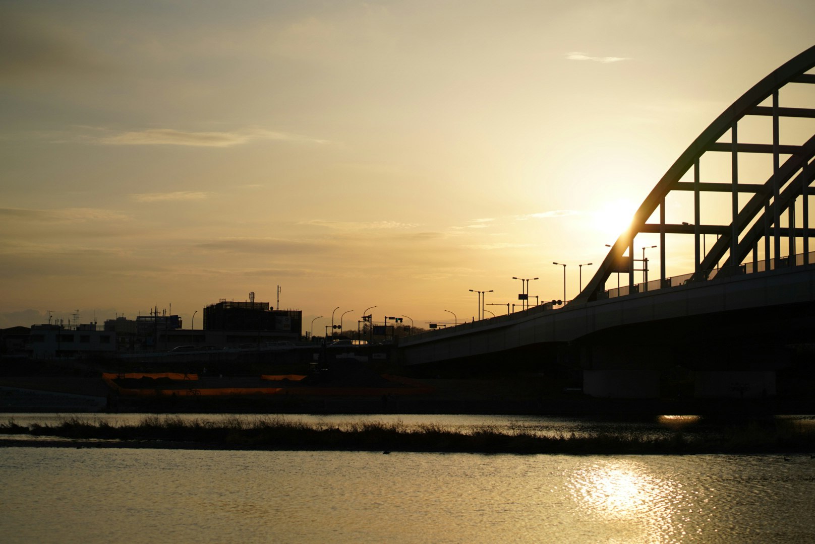 夕暮れの川沿いを走る橋と夕日