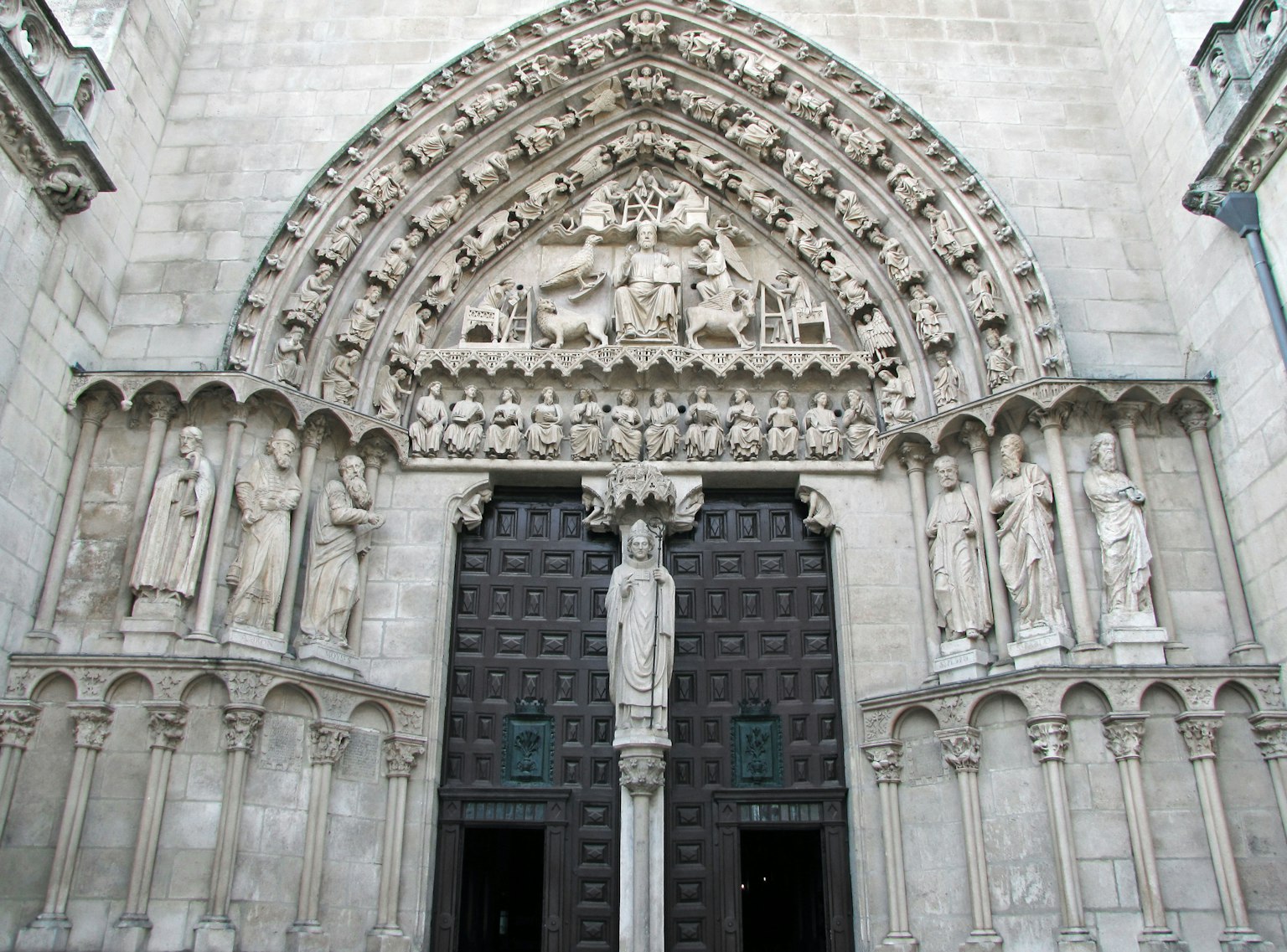 Façade d'église gothique avec des sculptures élaborées comportant de grandes portes et des figures de saints