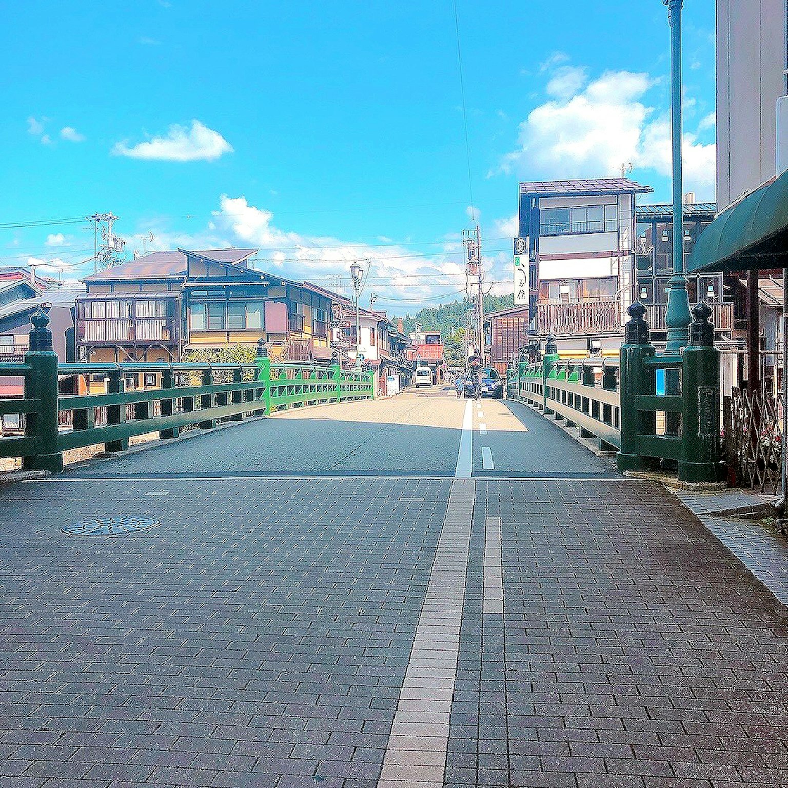 Green bridge under blue sky with surrounding buildings