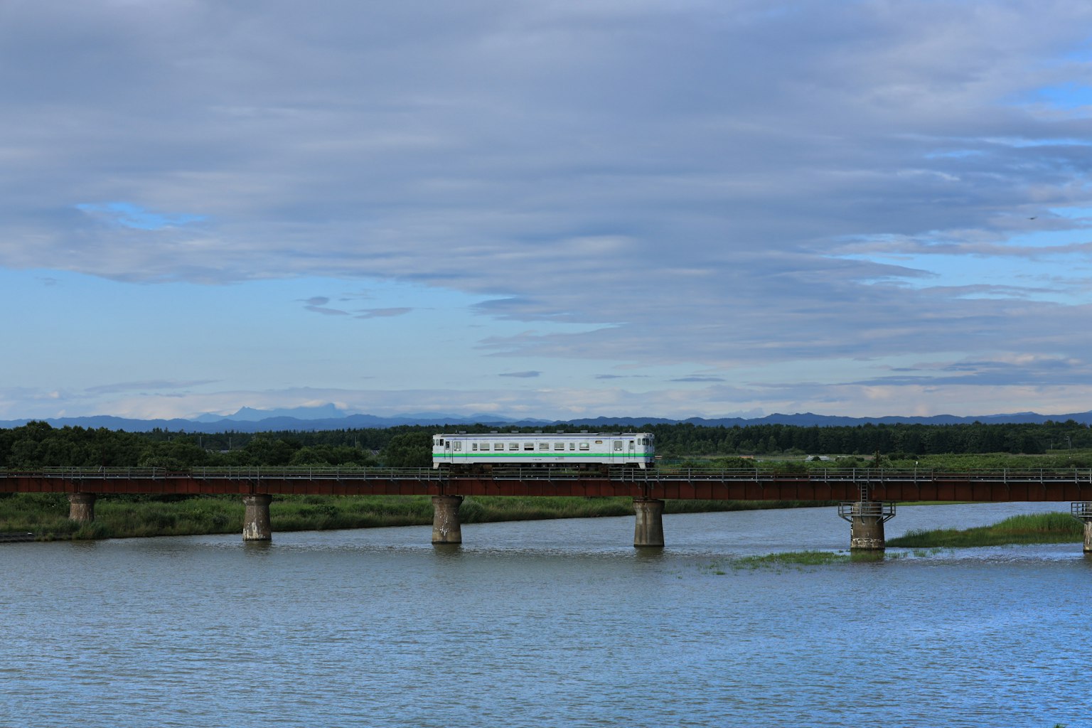 Treno che attraversa un fiume sotto un cielo blu