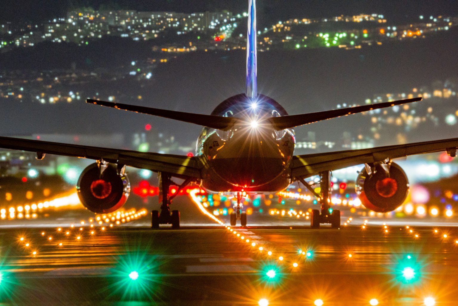 Airplane on runway at night with colorful lights illuminating the scene