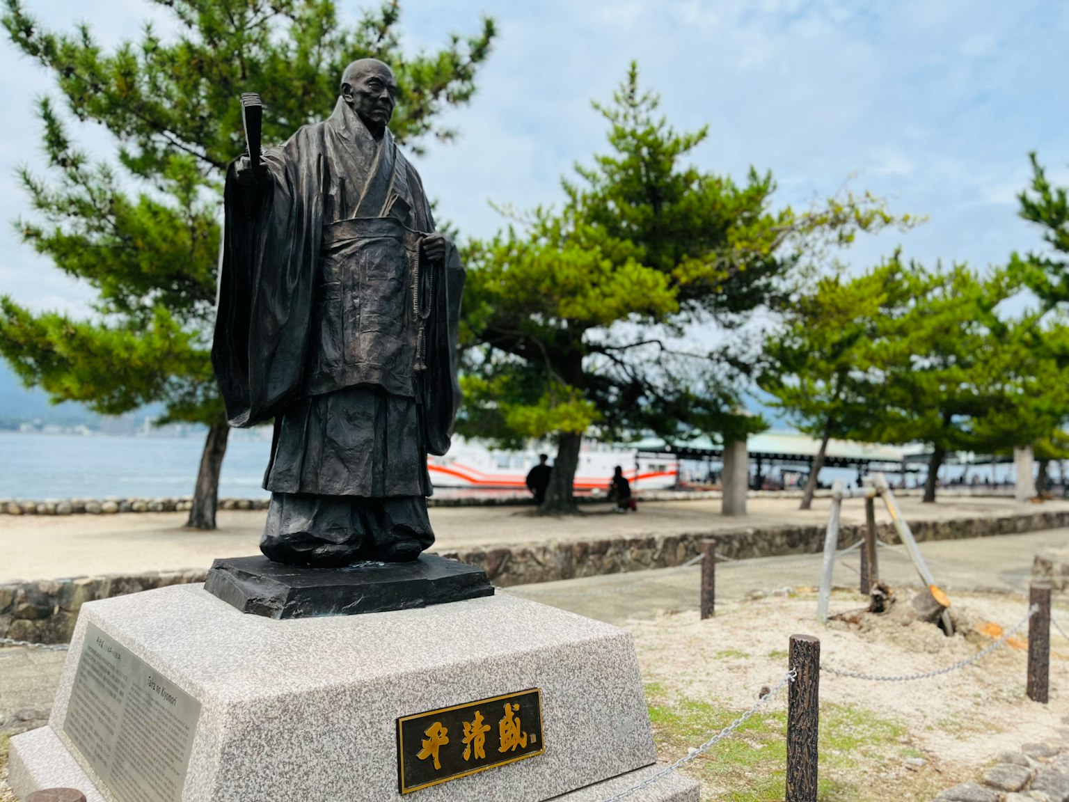 Estatua de pie cerca del mar rodeada de árboles verdes y cielo azul