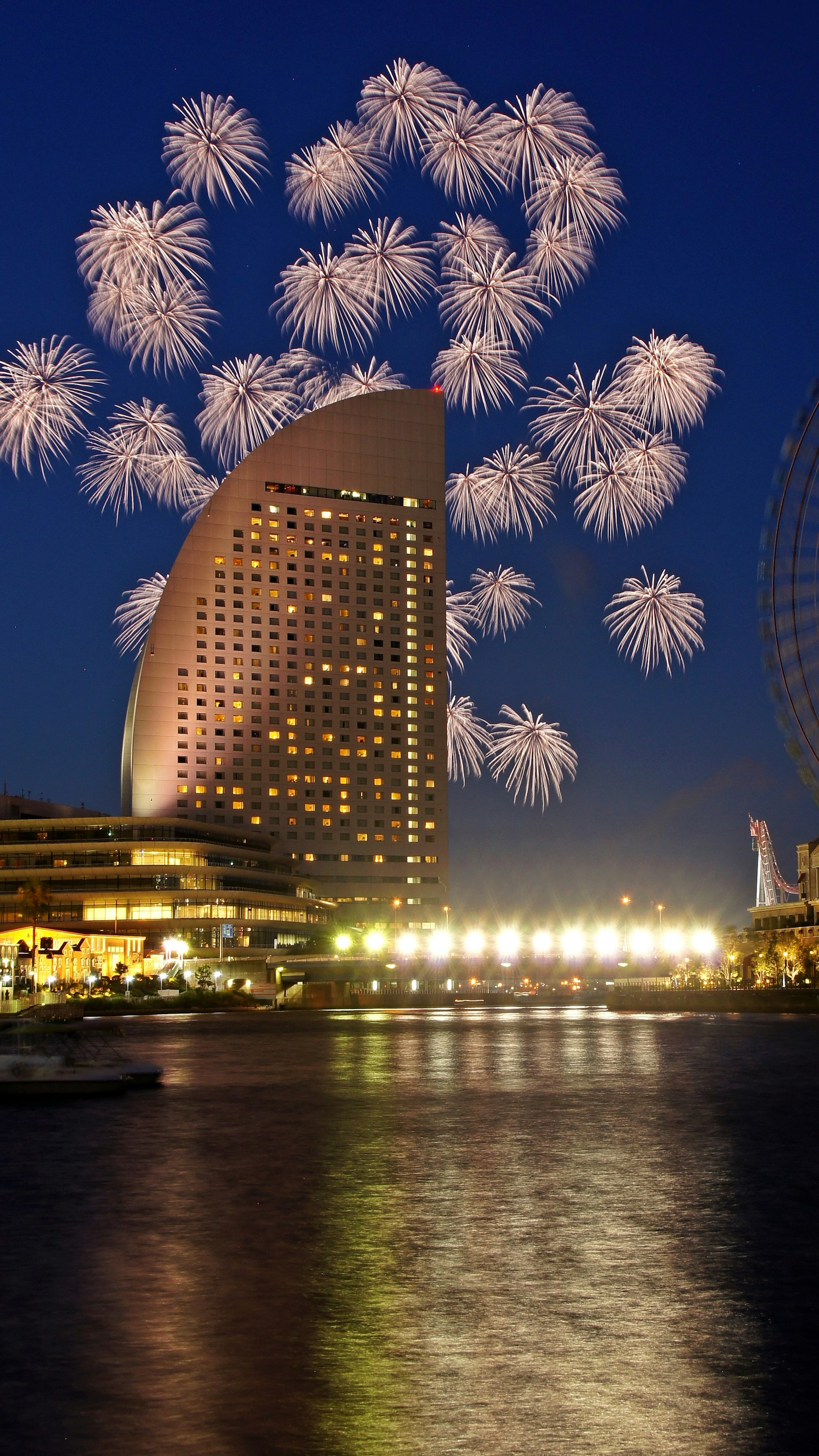 I fuochi d'artificio illuminano il cielo notturno sopra la Yokohama Landmark Tower