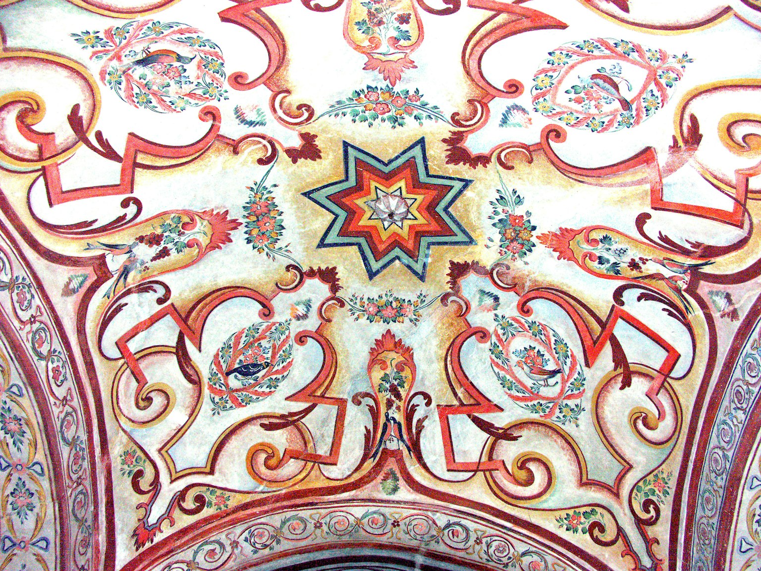 Lebendiges Deckendesign mit aufwendigen Verzierungen farbenfrohe Sternform in der Mitte umgeben von floralen und geometrischen Mustern