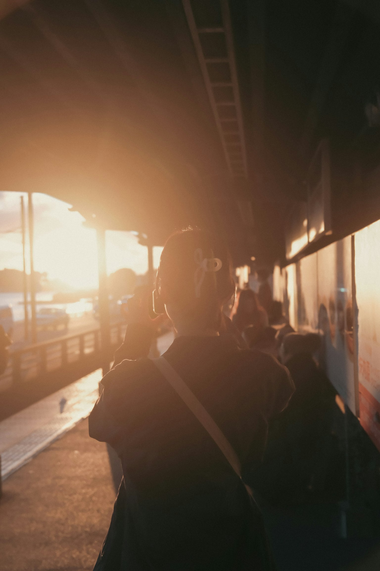 Una persona caminando por una acera con la espalda al atardecer, rodeada de otras personas
