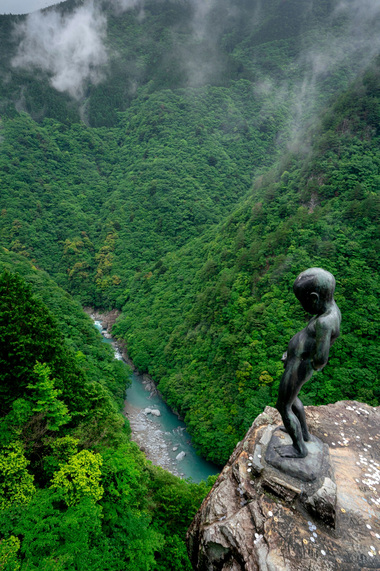 Skulptur mit Blick auf ein grünes Tal und einen fließenden Fluss