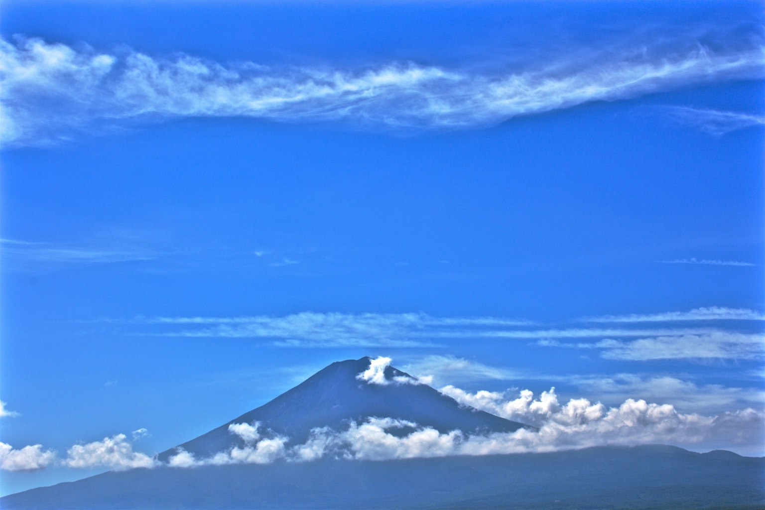 Montaña sobre las nubes bajo un cielo azul