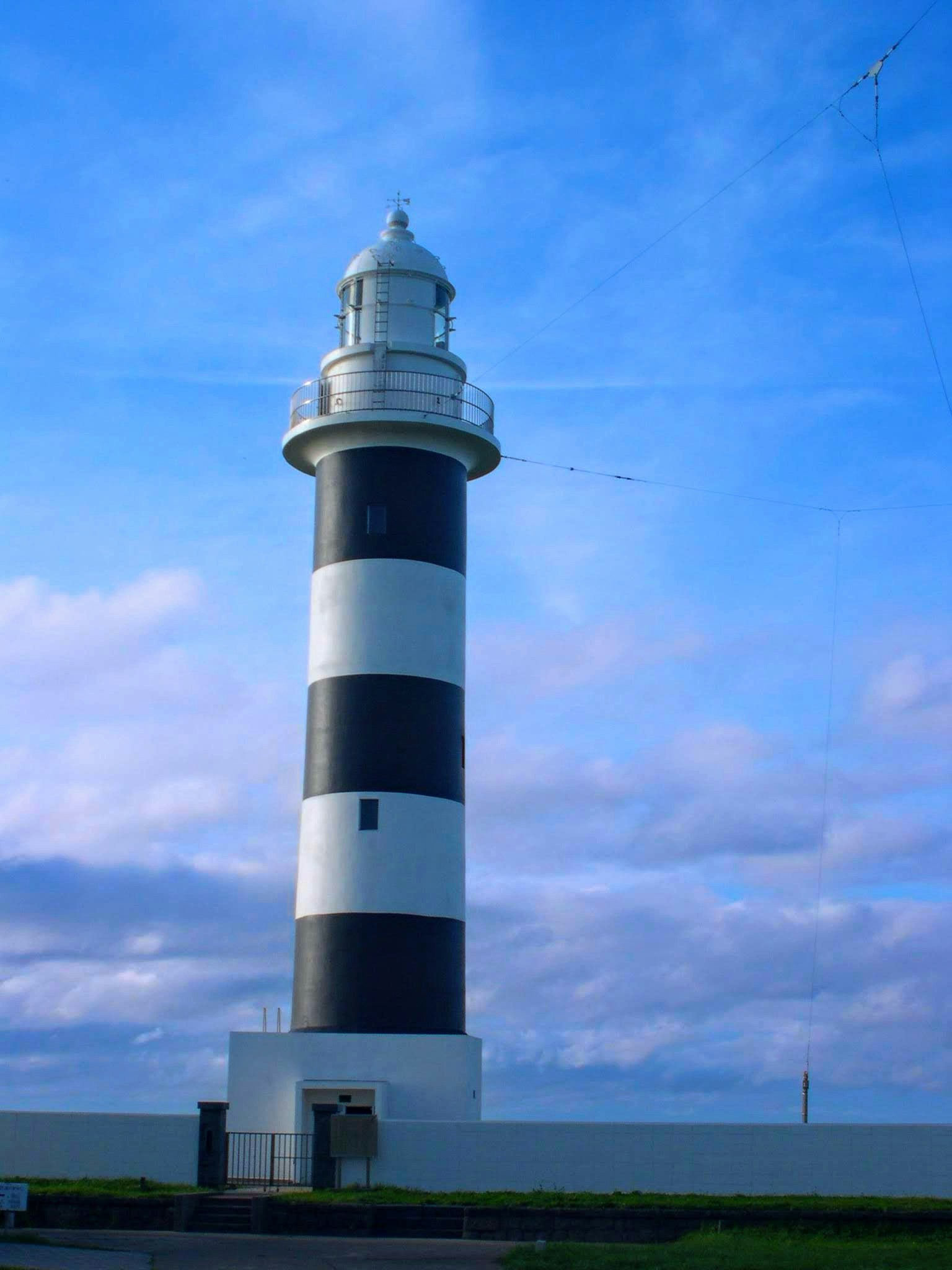 Mercusuar bergaris hitam dan putih di bawah langit biru