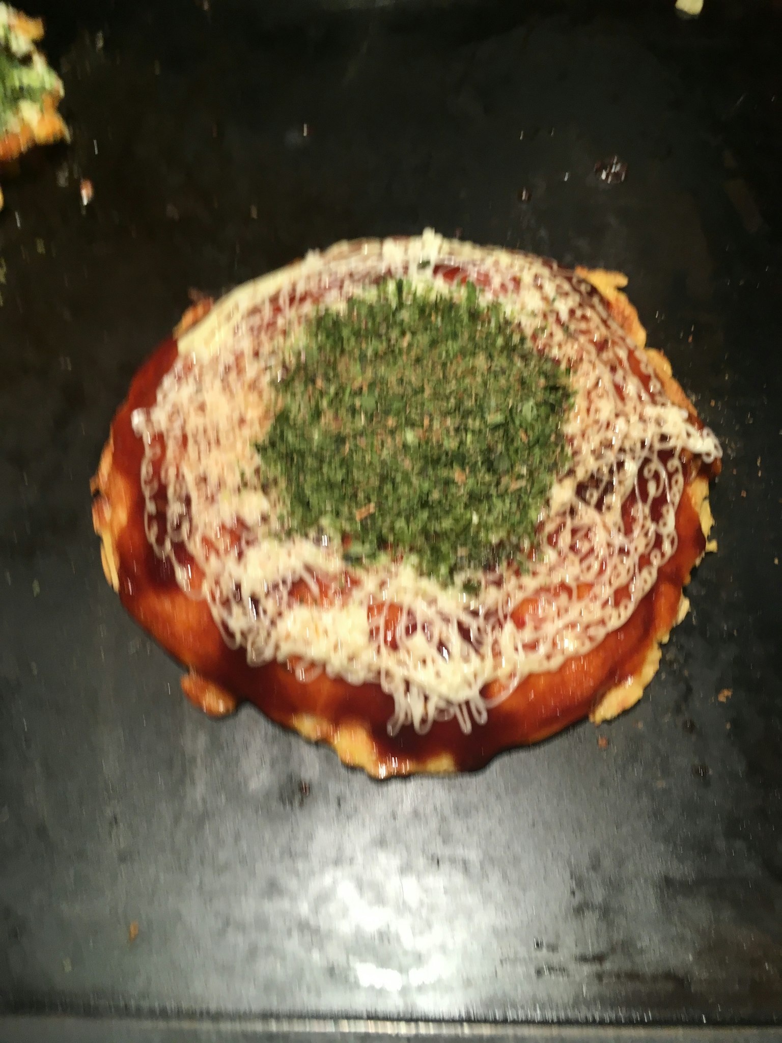 黑色烤盘上的披萨顶部有奶酪和香草
