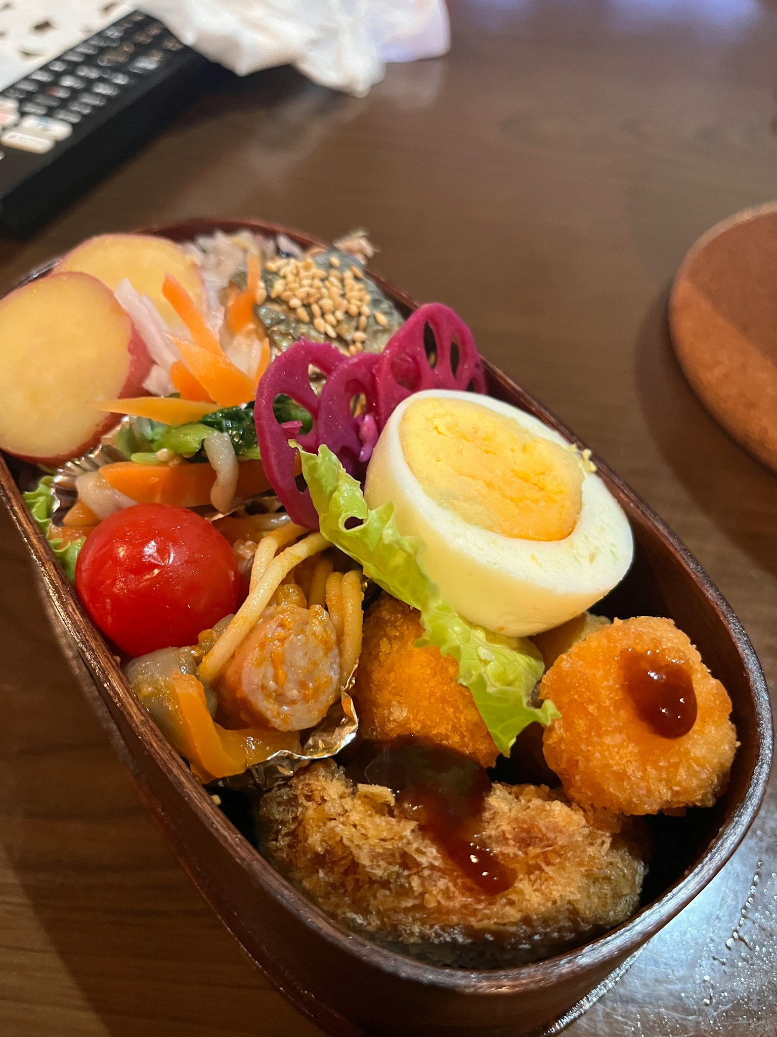 Kotak bento yang diisi dengan bahan berwarna-warni termasuk telur rebus, udang goreng, dan sayuran