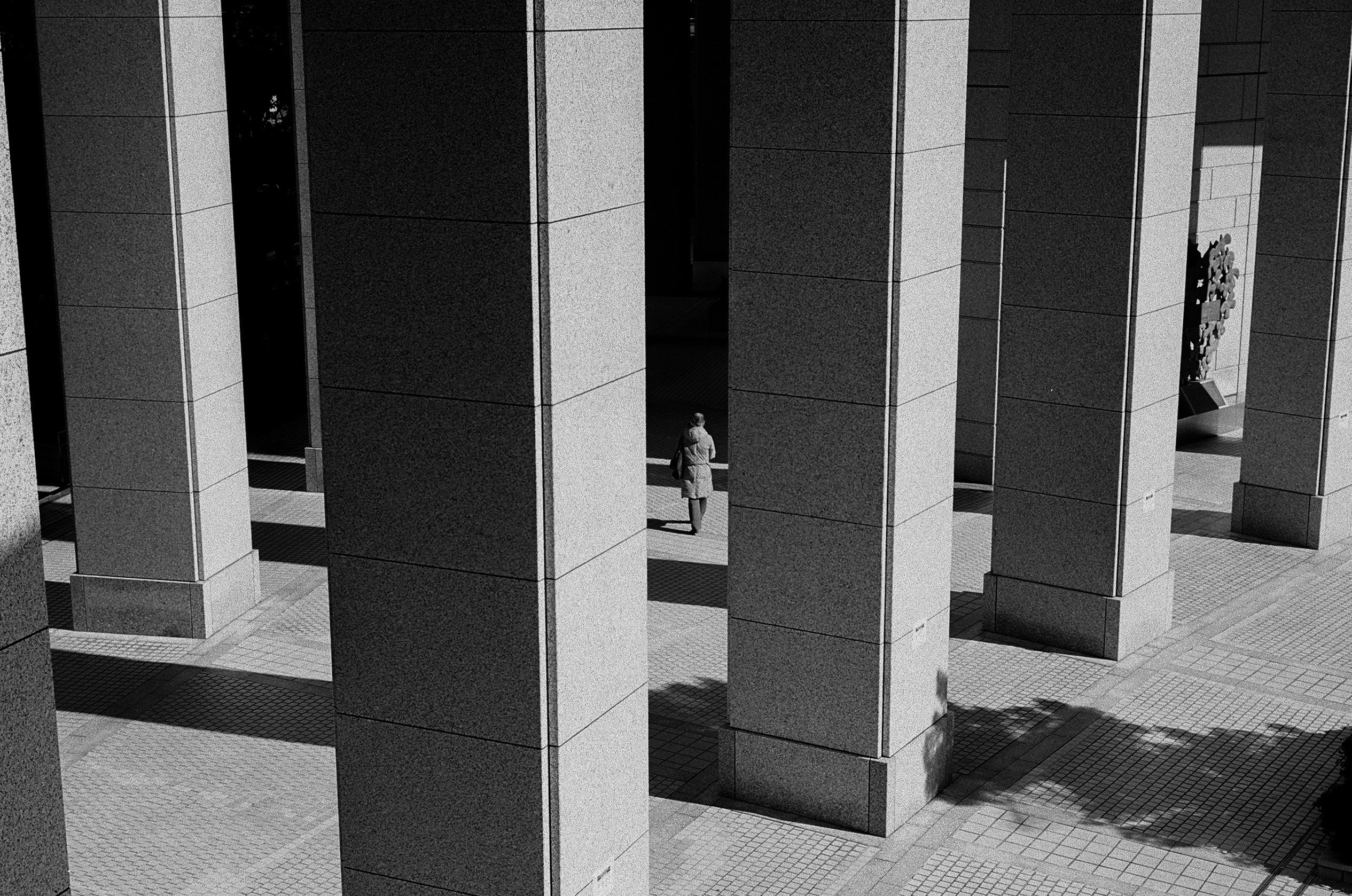 passage monochrome avec des colonnes répétées et une personne au loin