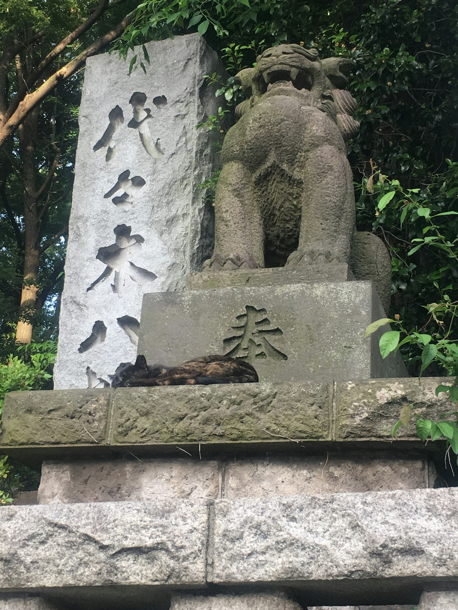 Stone komainu statue in a shrine surrounded by greenery
