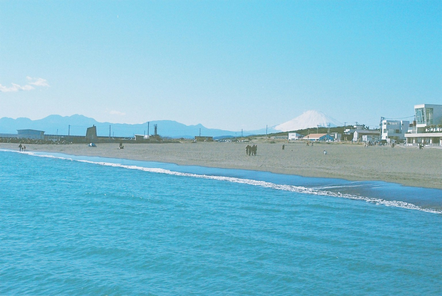 Vista panoramica di un oceano blu e una spiaggia di sabbia con montagne sullo sfondo