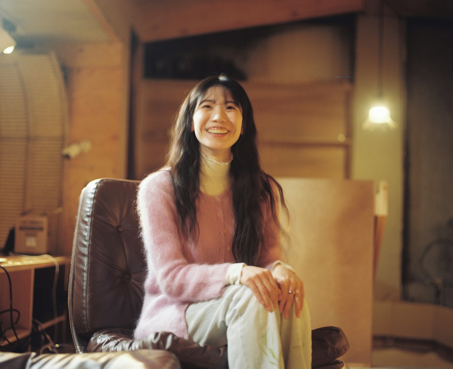 一位穿着柔和色彩毛衣的女性在室内微笑