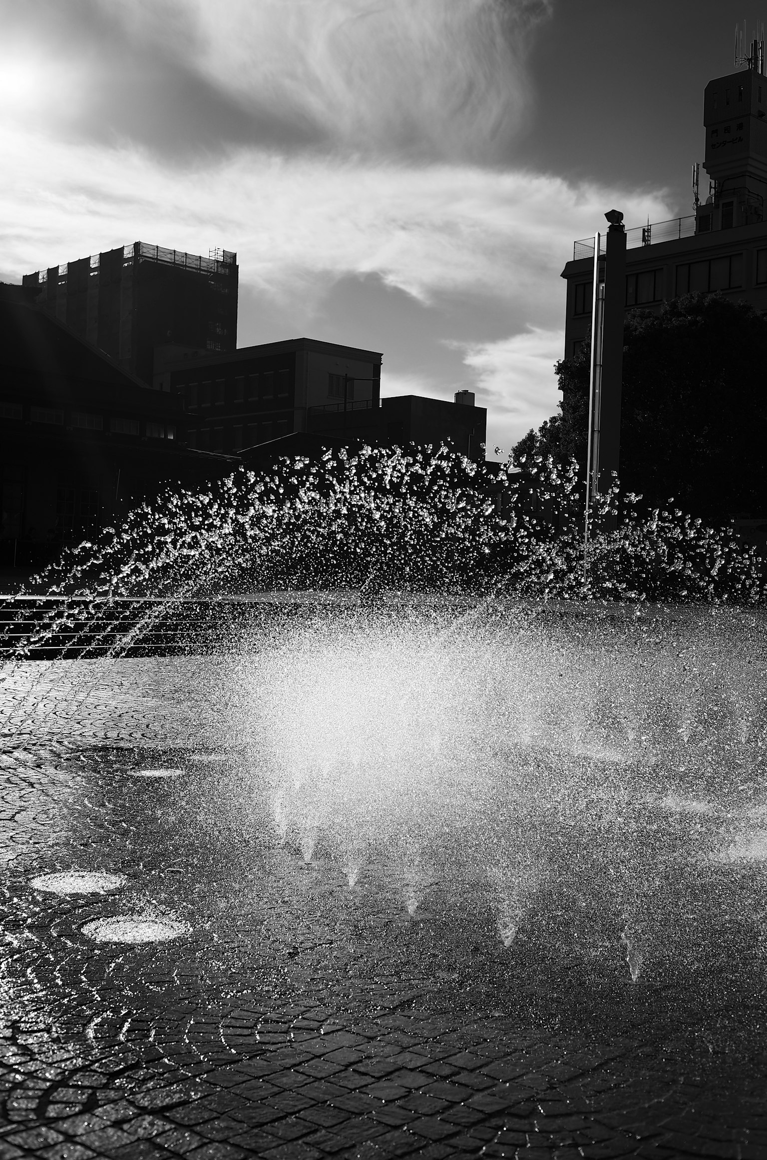 Fontaine en noir et blanc avec des éclaboussures d'eau dans une place