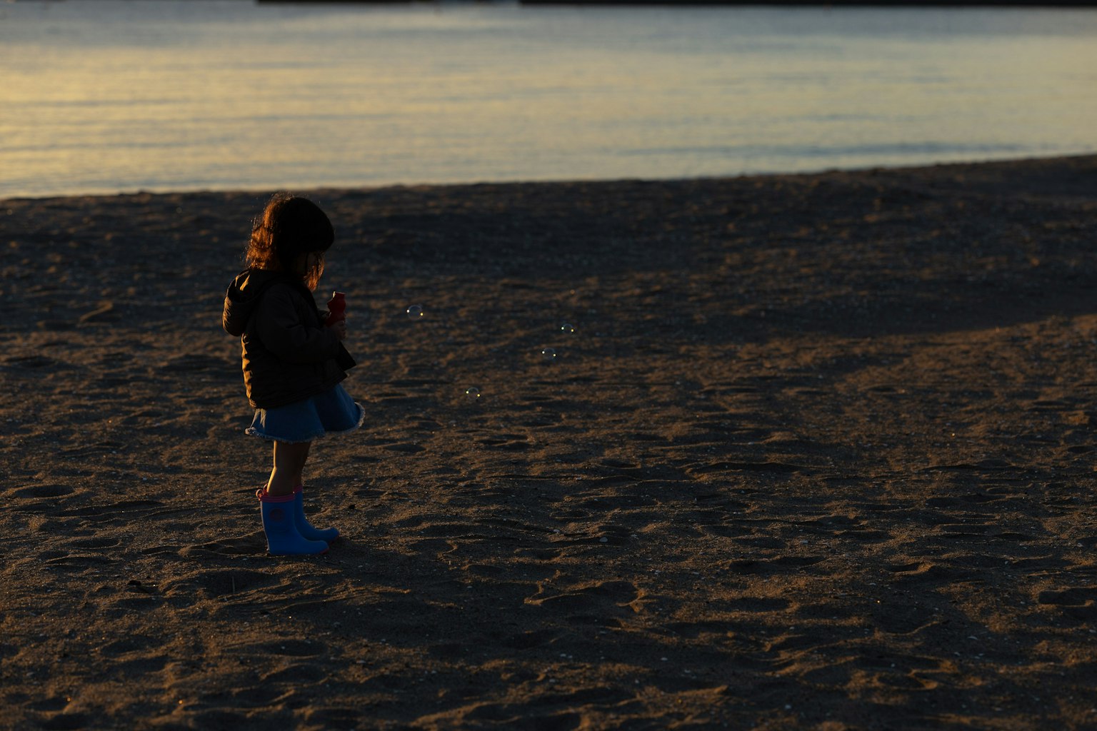 Siluet anak bermain di pantai saat matahari terbenam