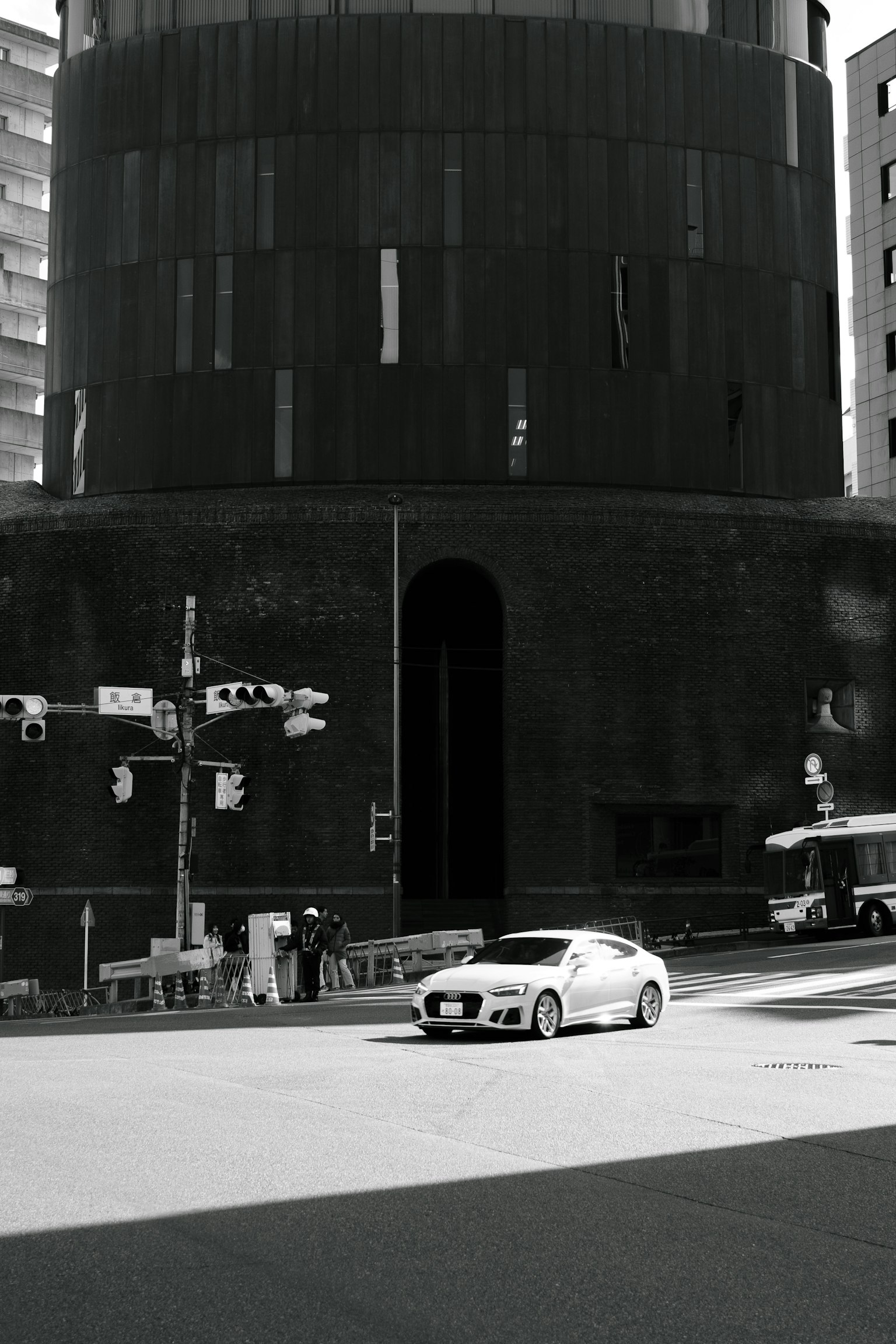 Auto bianca che passa davanti a un edificio nero con semafori all'angolo della strada