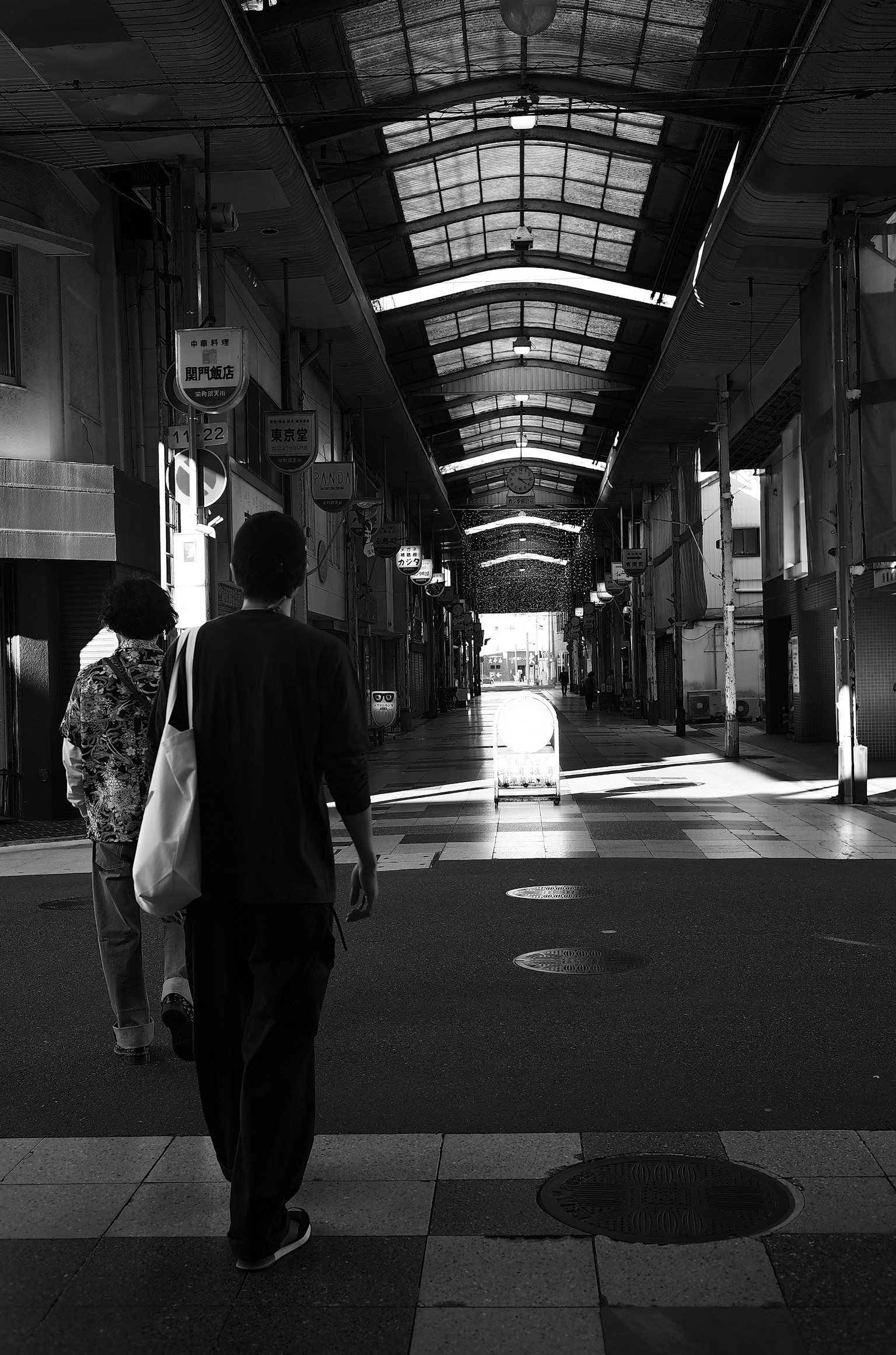 Silhouette of people walking in a black and white shopping arcade