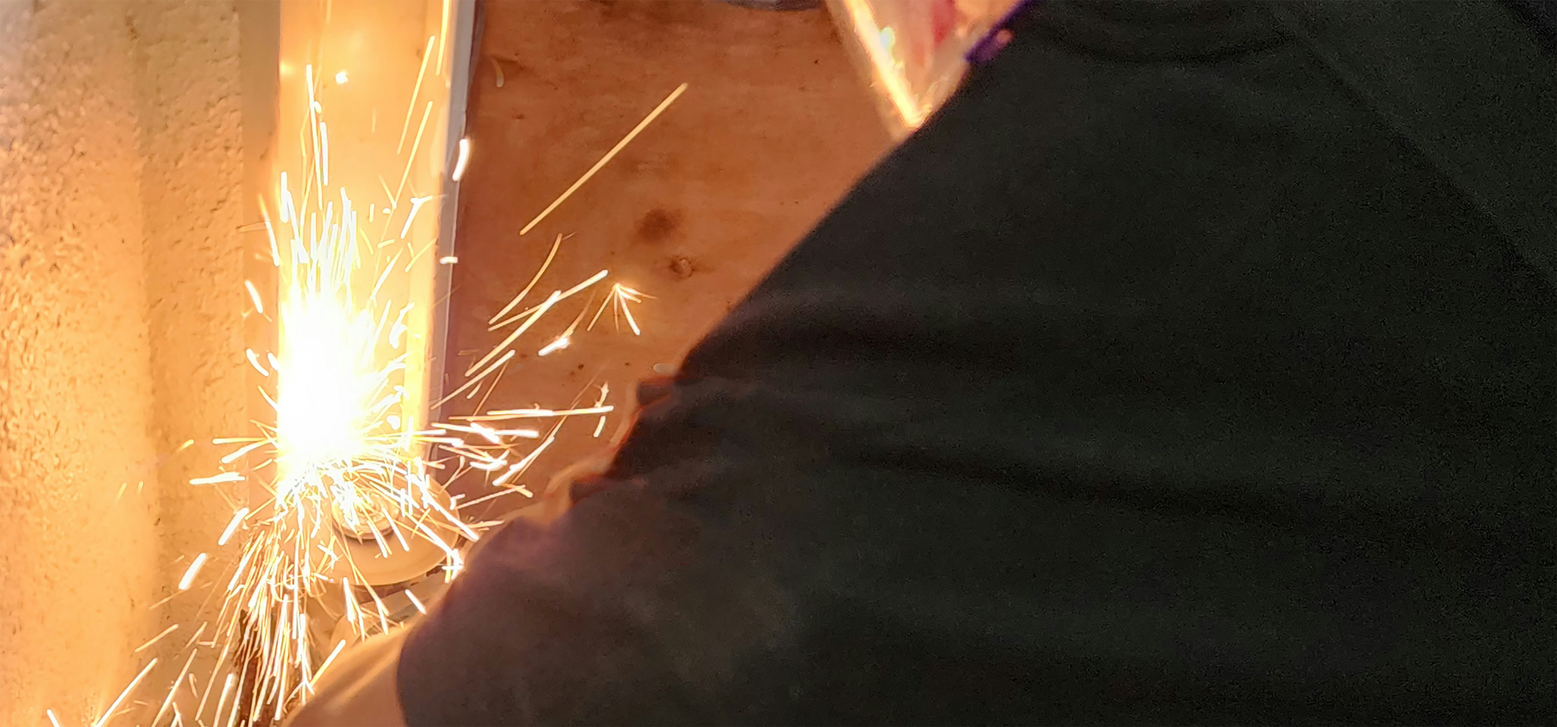 close-up of welding sparks and a worker’s arm