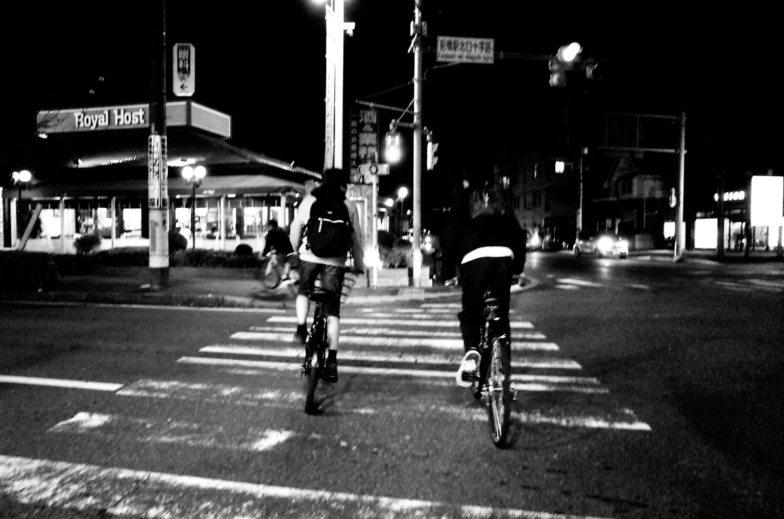 Due ciclisti in bicicletta di notte in un incrocio urbano con semafori