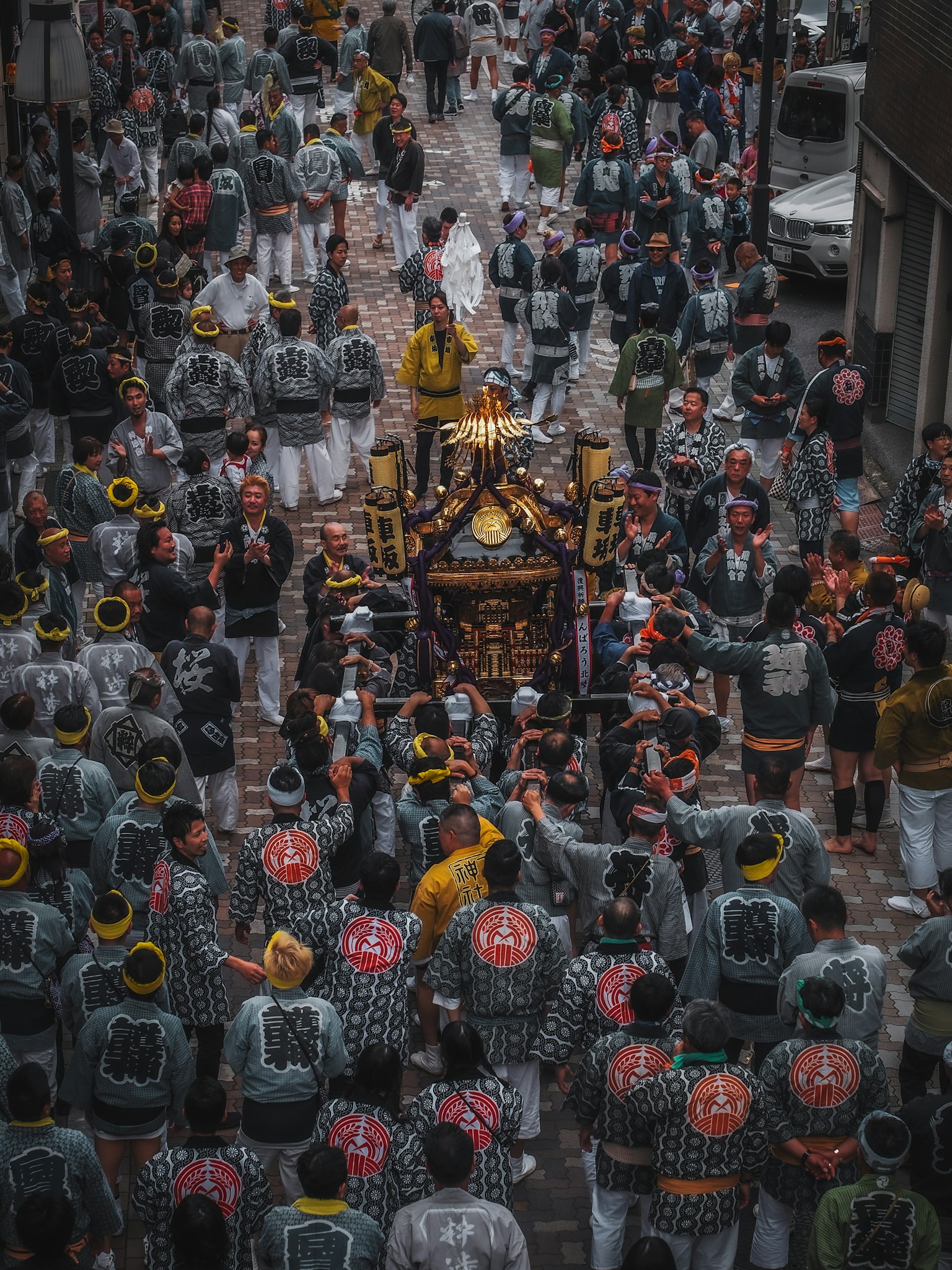ฝูงชนที่แบกศาลเจ้าขนาดเล็กในระหว่างเทศกาลในถนนที่พลุกพล่าน