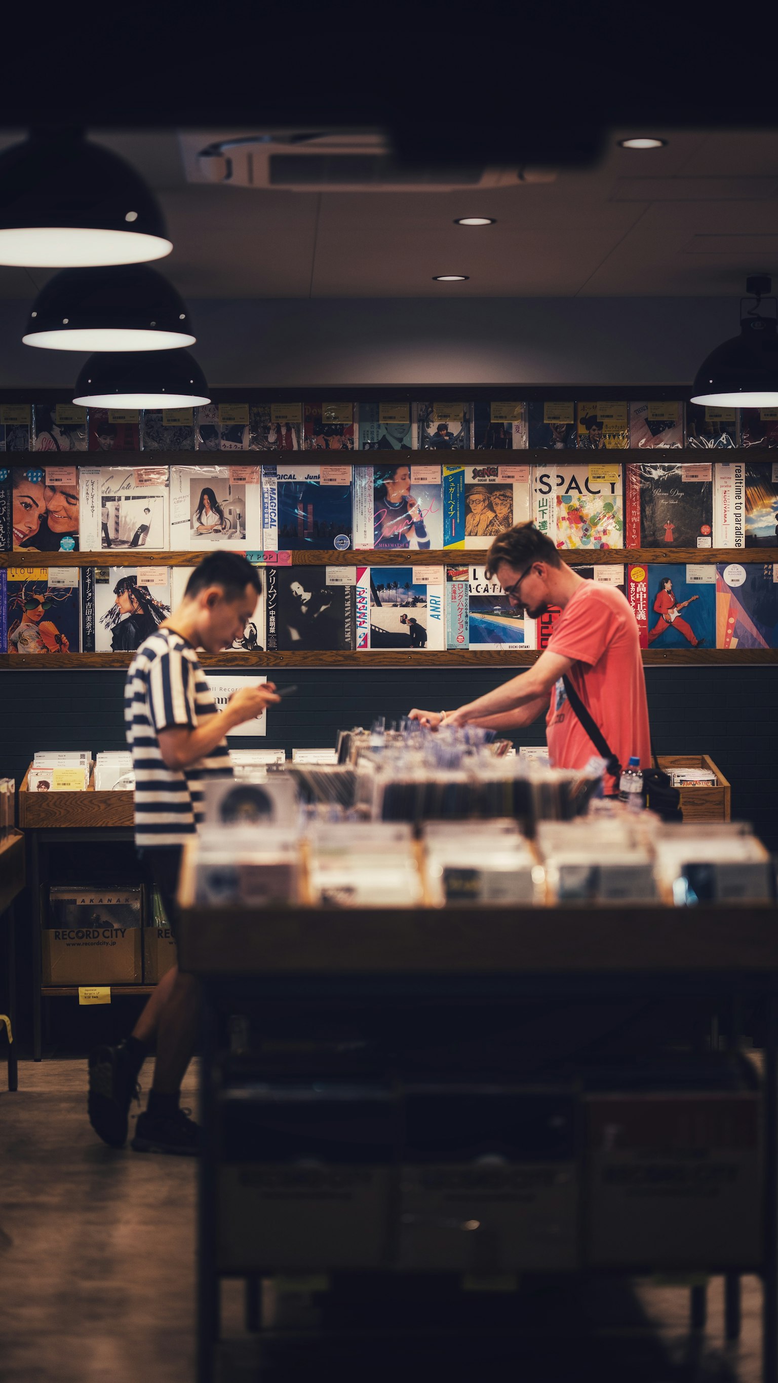 レコード店でレコードを探す二人の男性とカラフルなアルバムカバー