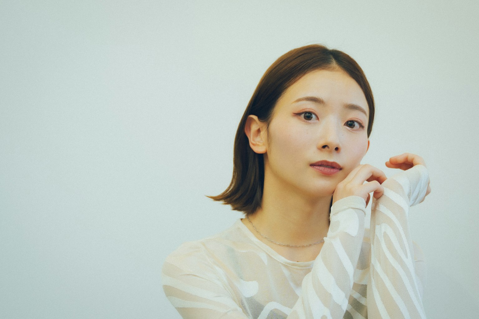 一位穿着透明白色上衣的女性在思考中摆姿势