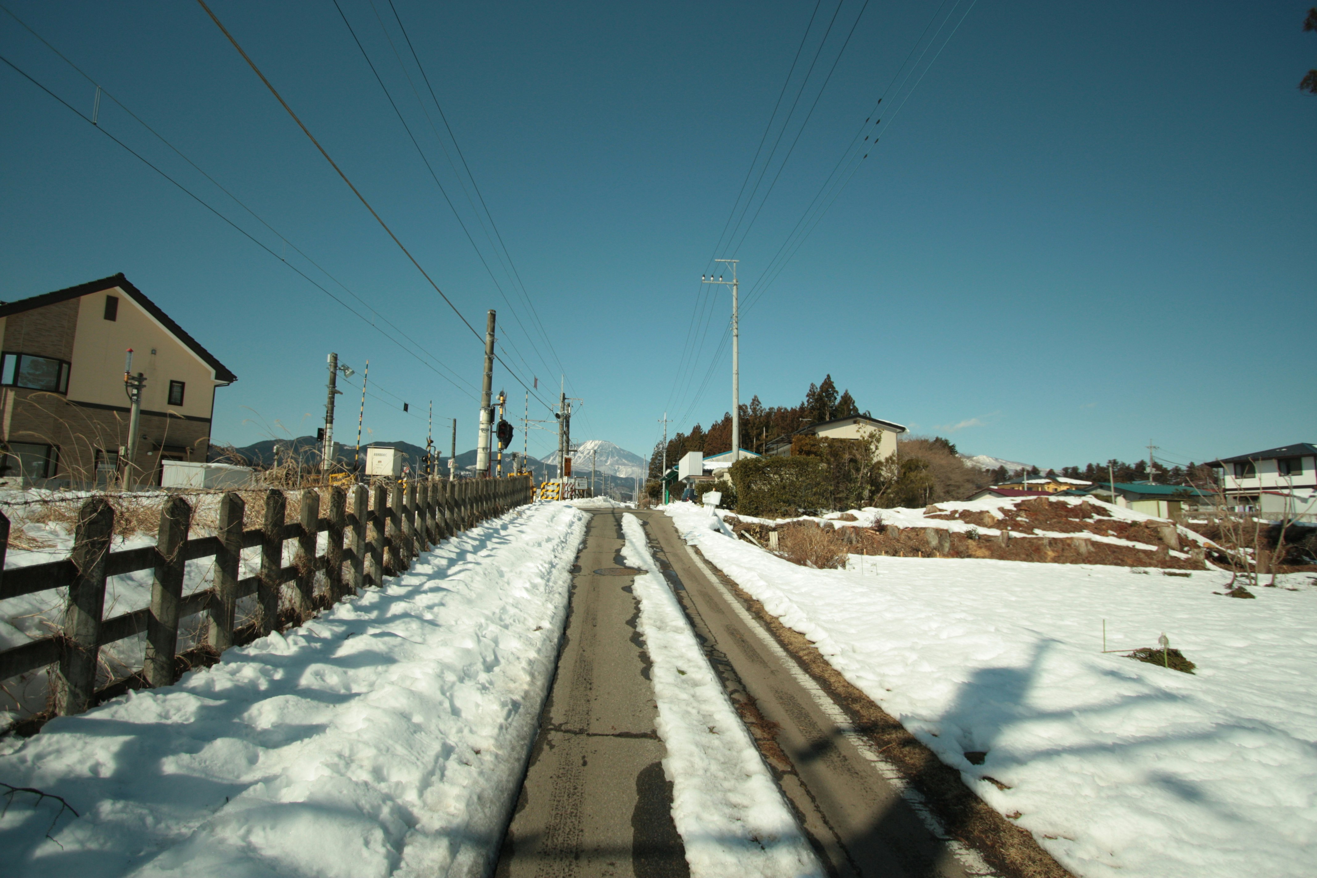 雪の積もった田舎道を走る直線の道路風景