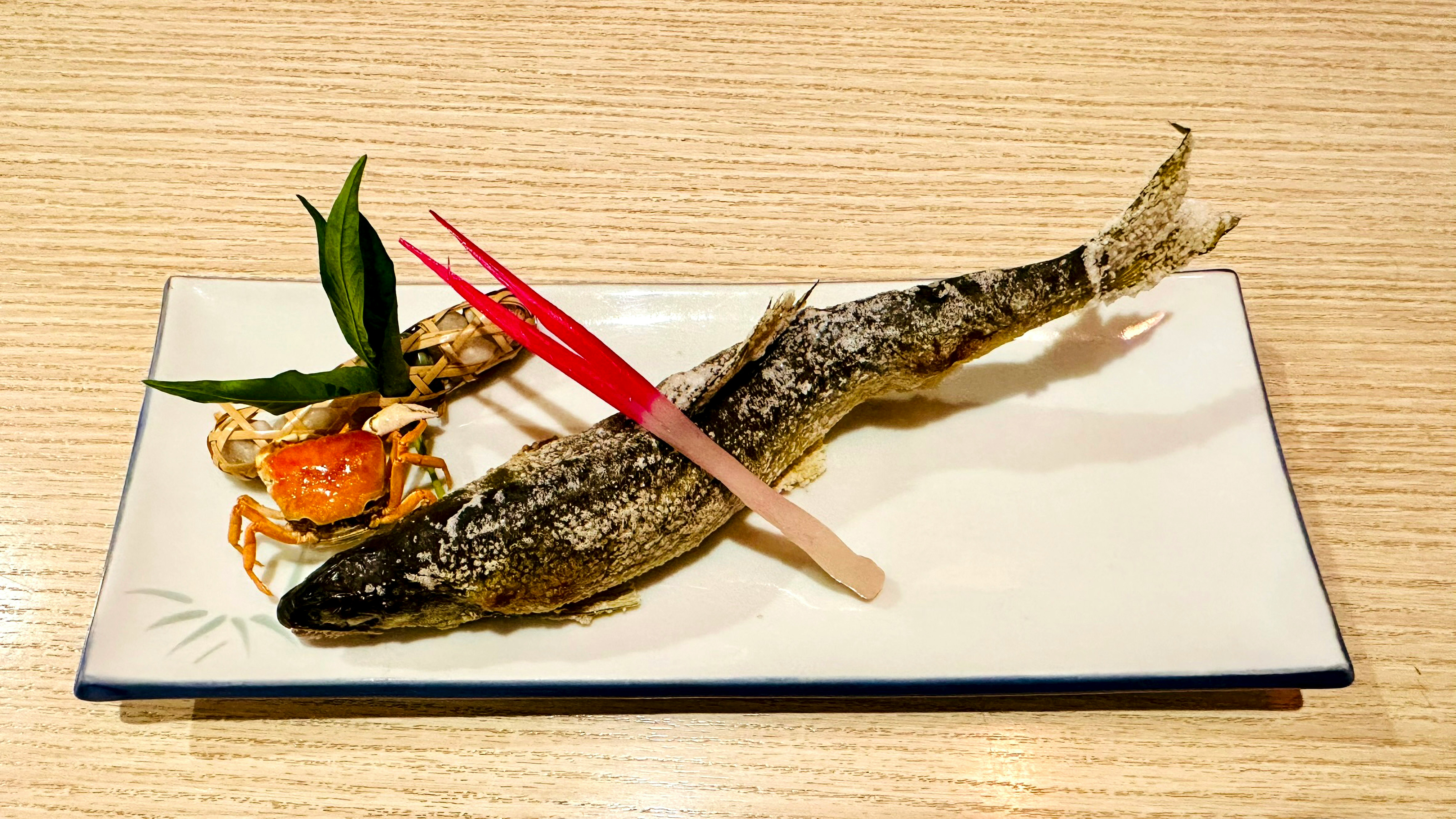 木目のテーブルに並ぶ焼き魚と付け合わせの盛り付け