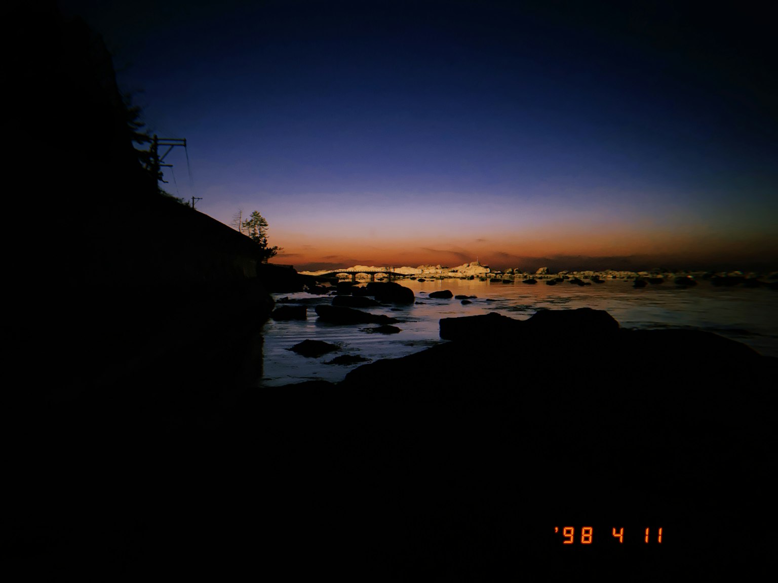 Silhouette of a coastline and rocks against a sunset sky