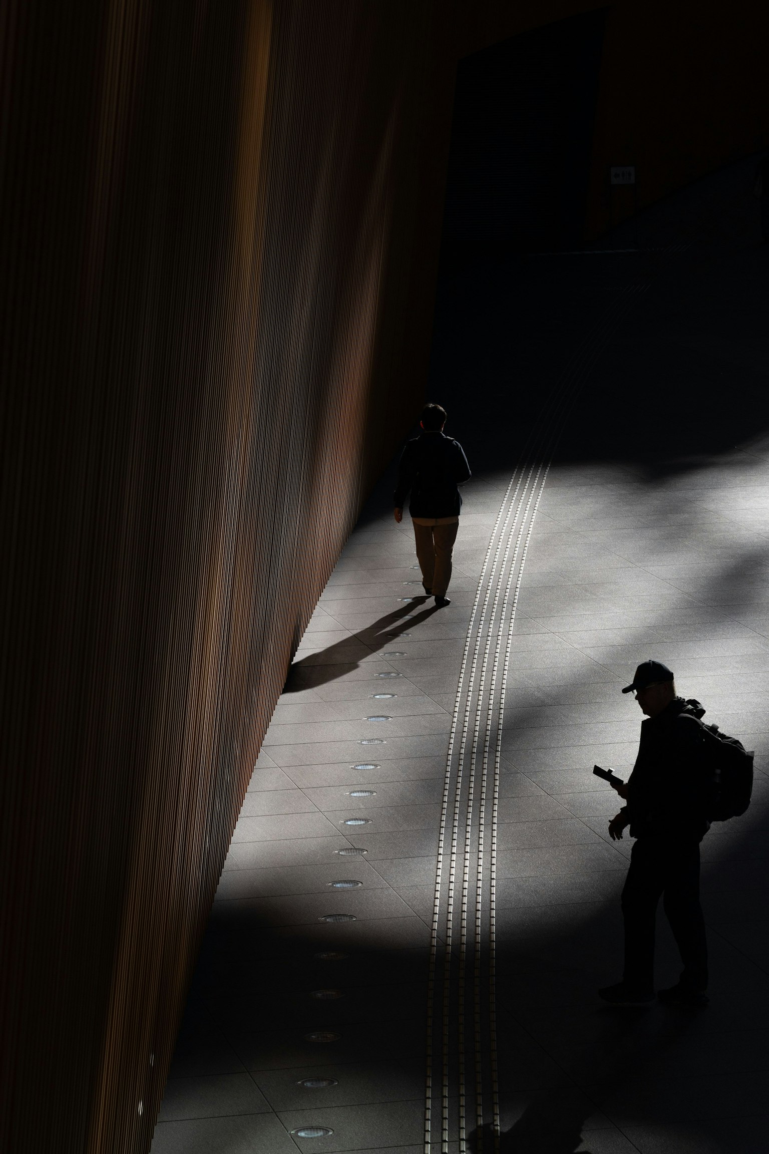 Siluetas de personas caminando en un dramático juego de luz y sombra en un entorno urbano
