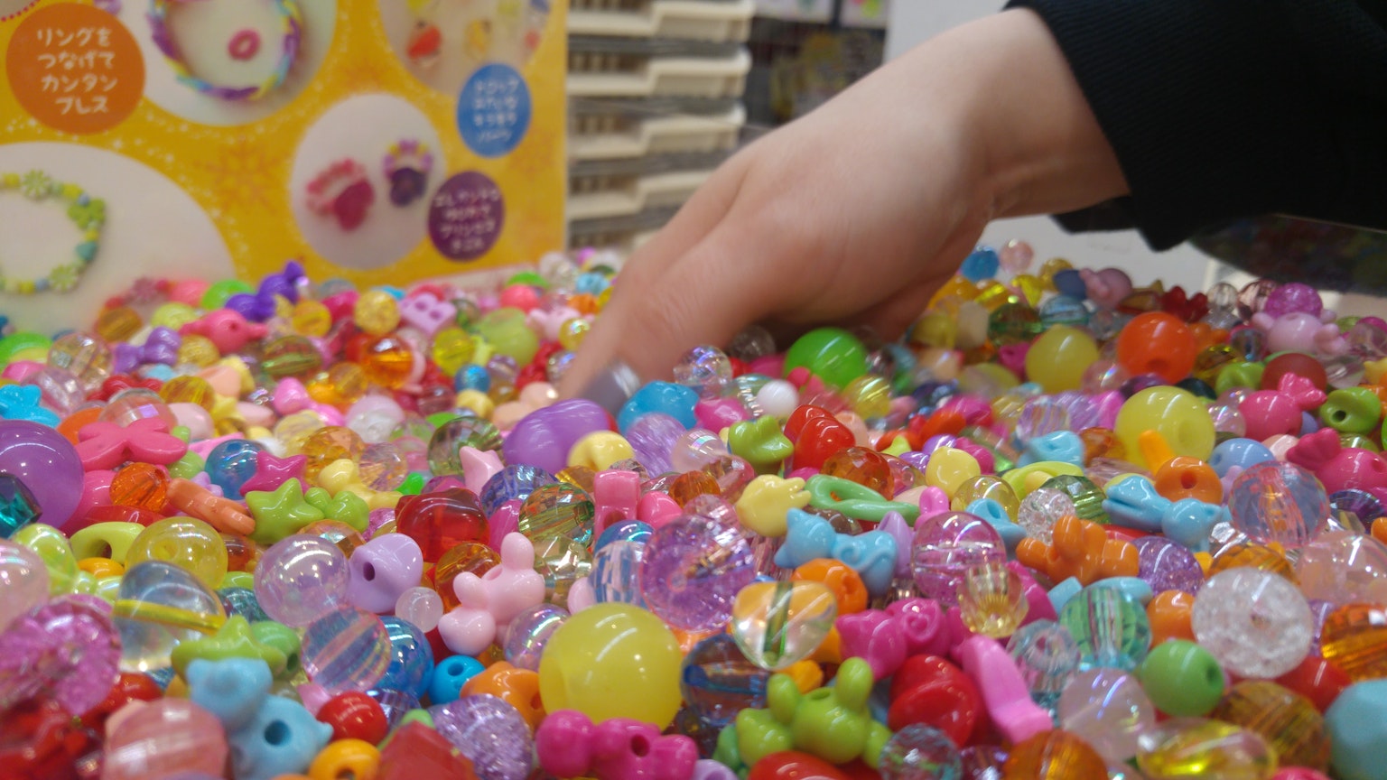 Une main plongeant dans un tas de perles colorées