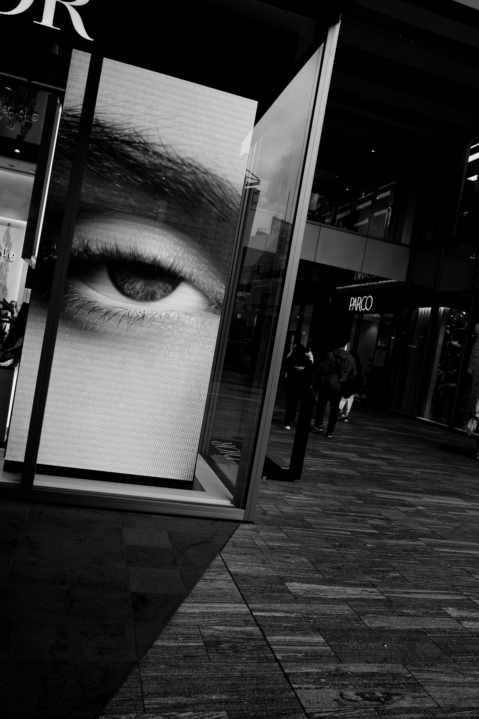 Close-up of a large eye displayed in a storefront with people in the background