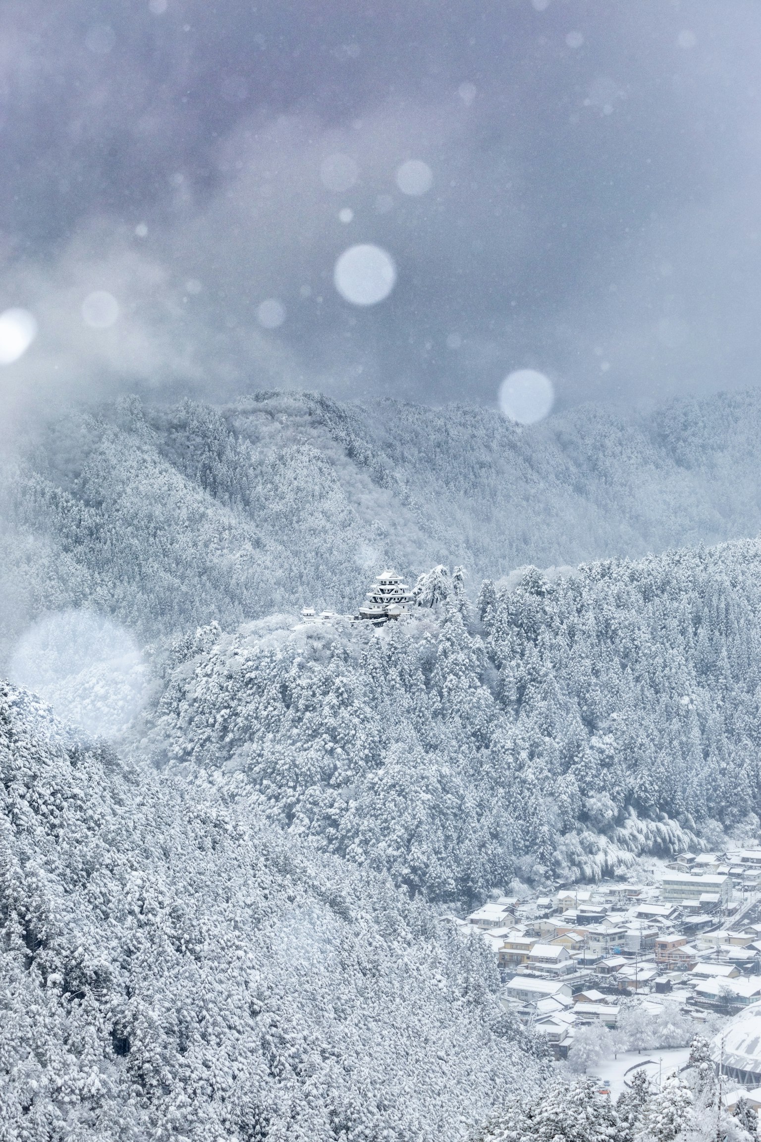 雪覆盖的山脉和村庄风景在多云的天空下