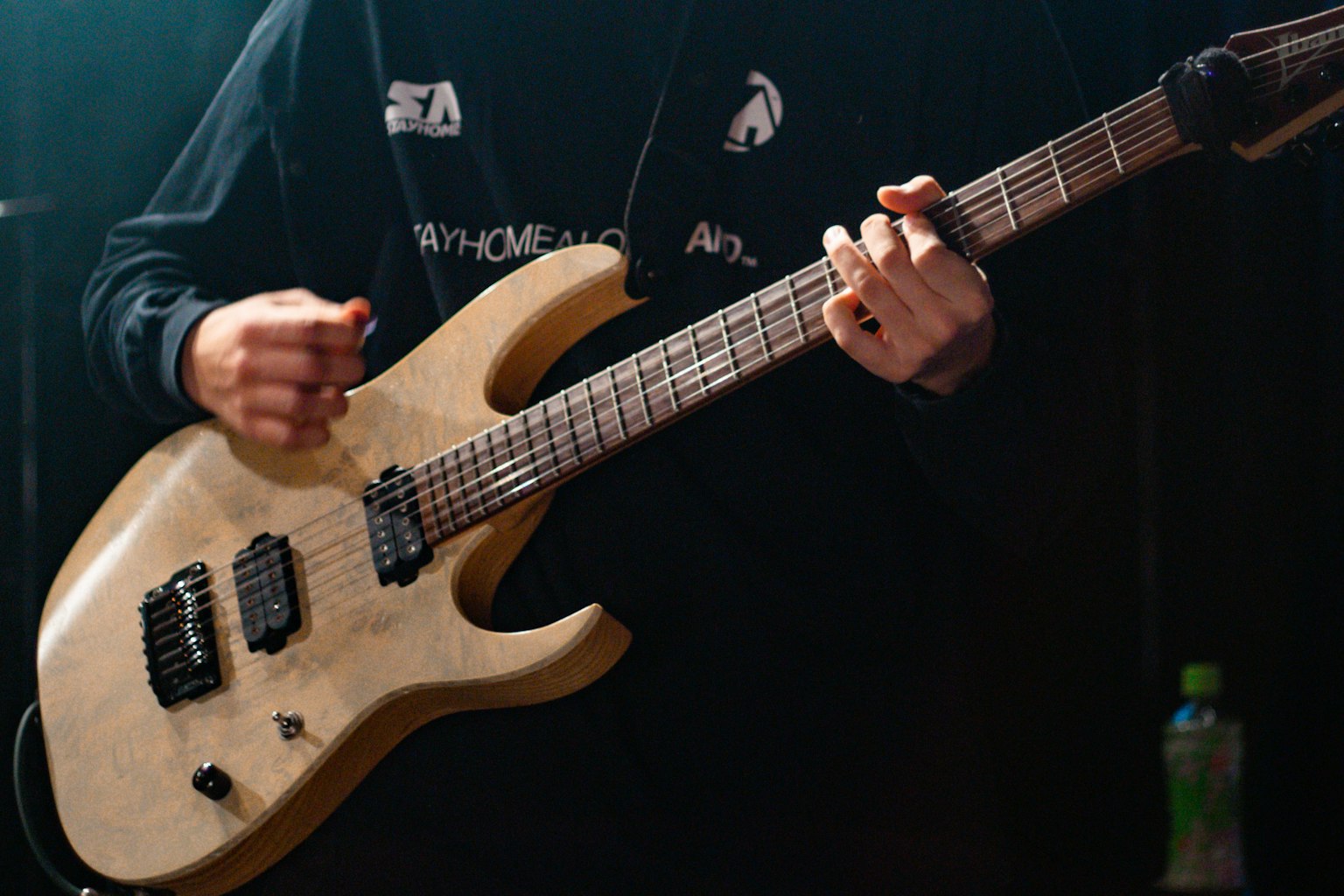 Nahaufnahme einer Hand, die eine hellfarbige E-Gitarre spielt