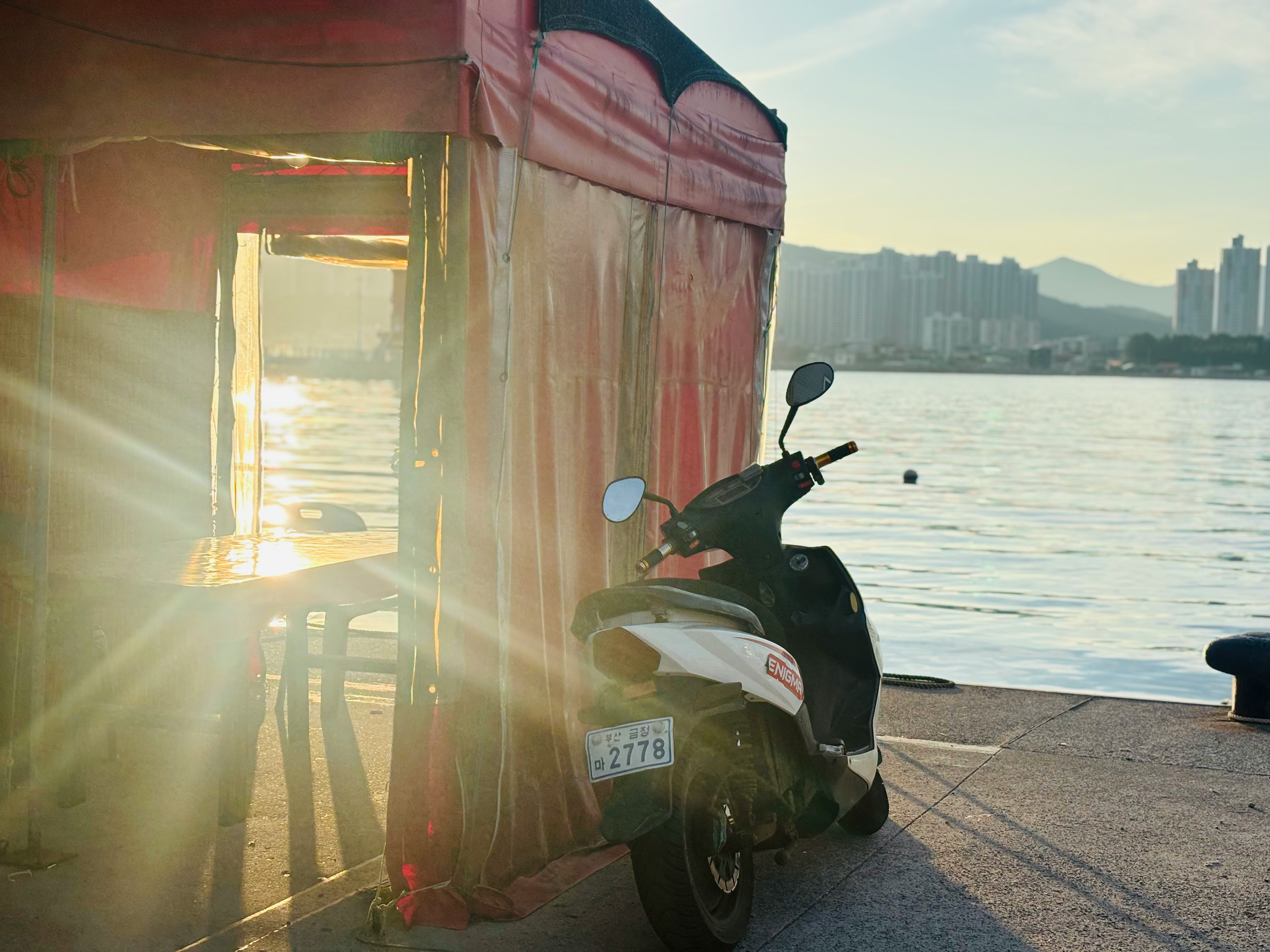 夕暮れの海沿いで停まるバイクと港の遊歩道