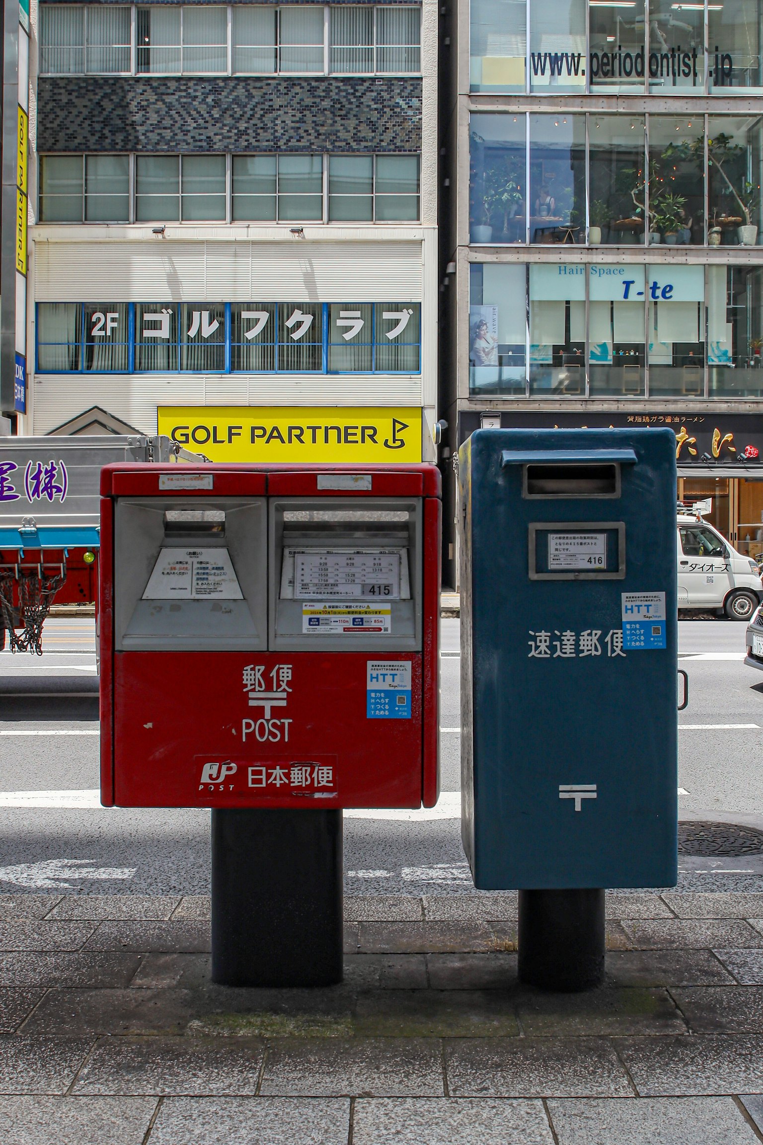 Hộp thư đỏ và xanh đứng cạnh nhau trong bối cảnh đô thị