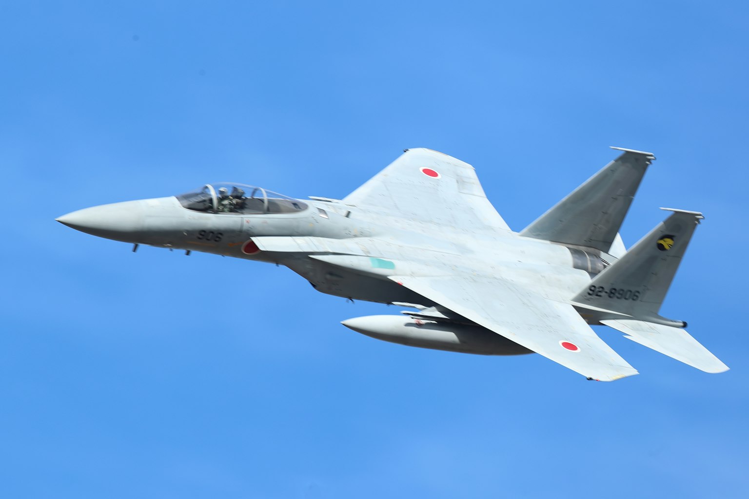 Sebuah jet tempur putih terbang di langit biru