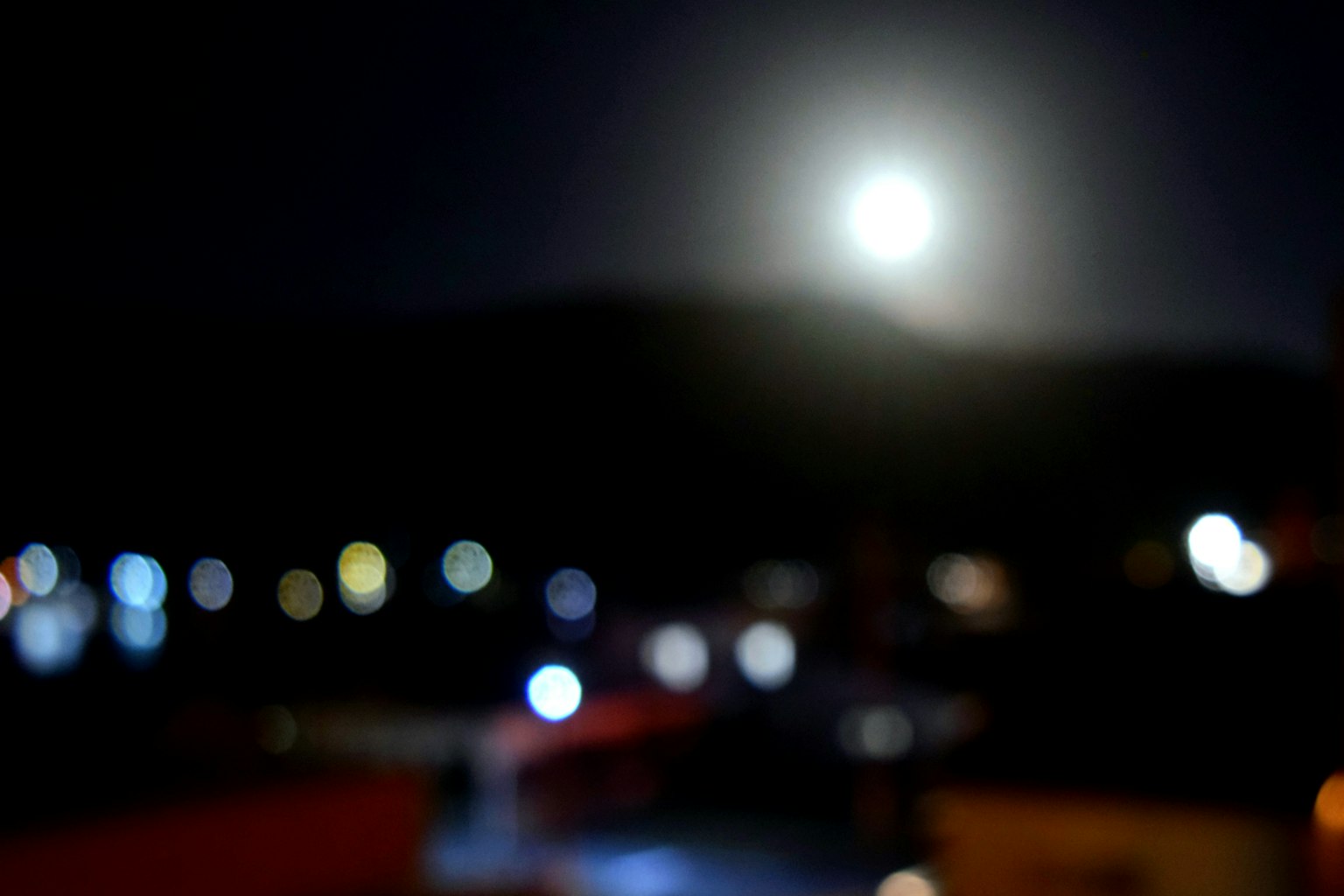 Verschwommene Nachtansicht mit einem hellen Mond und bunten Lichtern