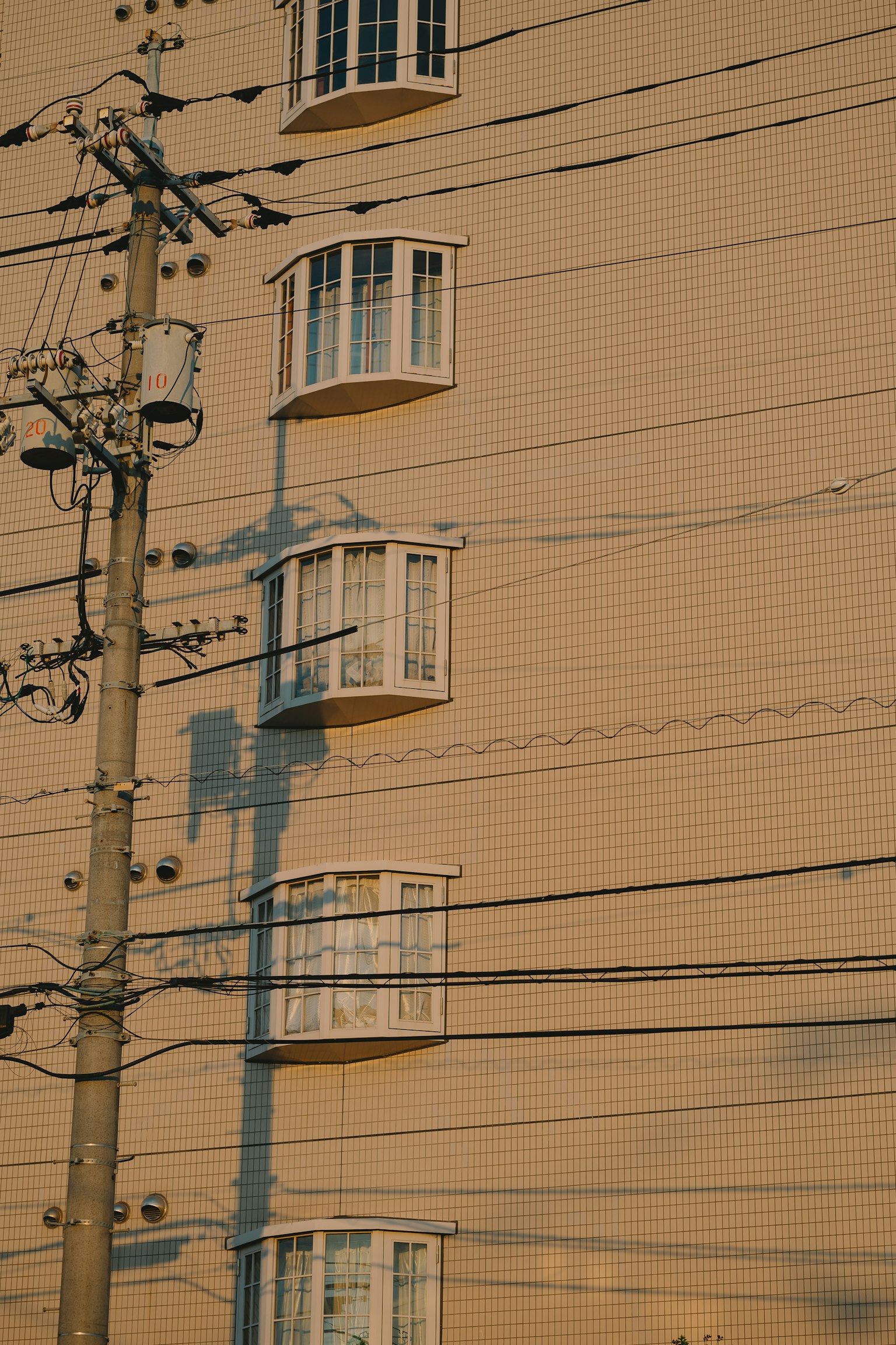 Sunlit building wall with unique windows and power lines