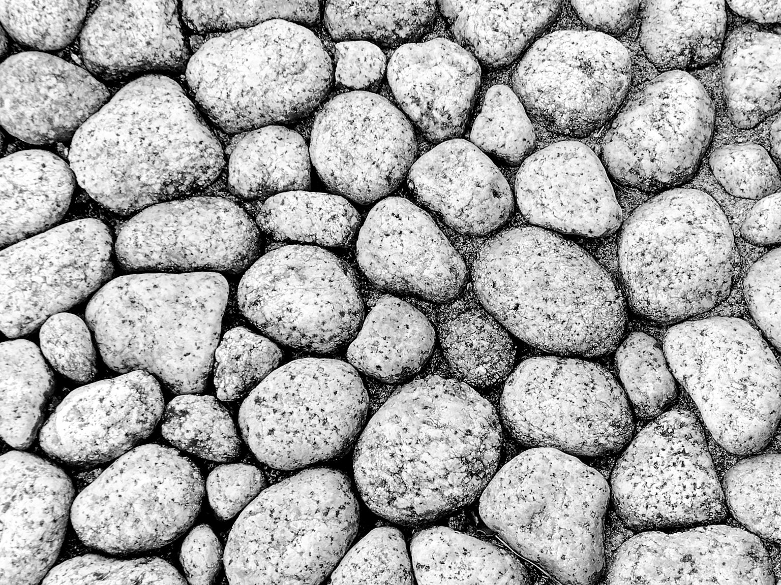 A textured arrangement of various shapes and sizes of black and white stones